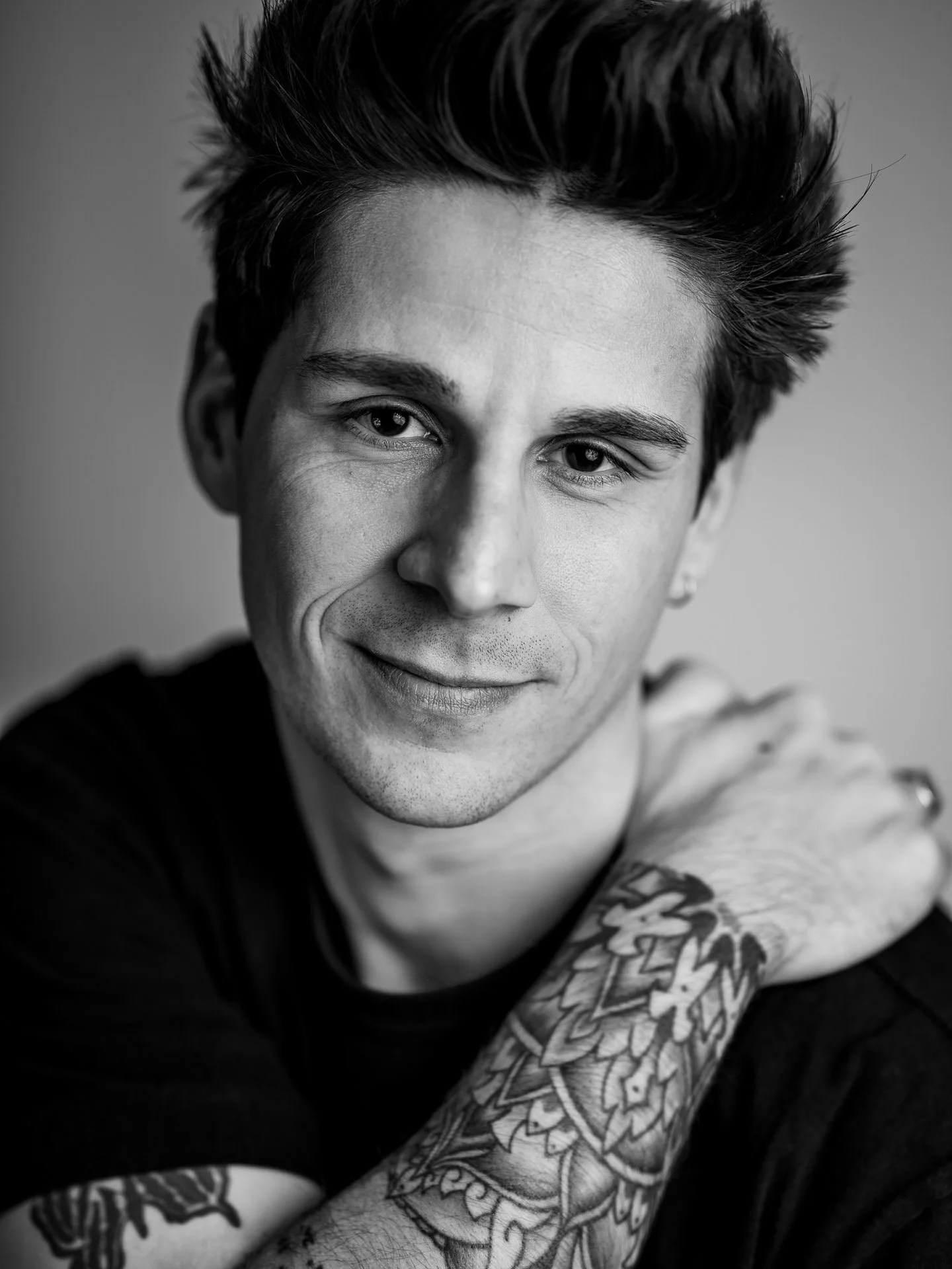  Black and white studio portrait of a young man with tatoos 