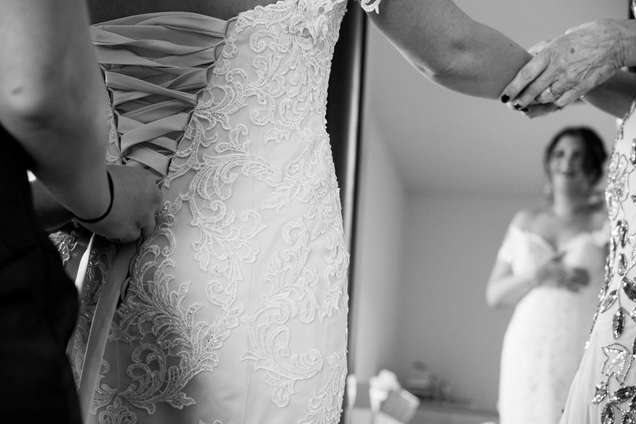 Bride getting wedding dress laced