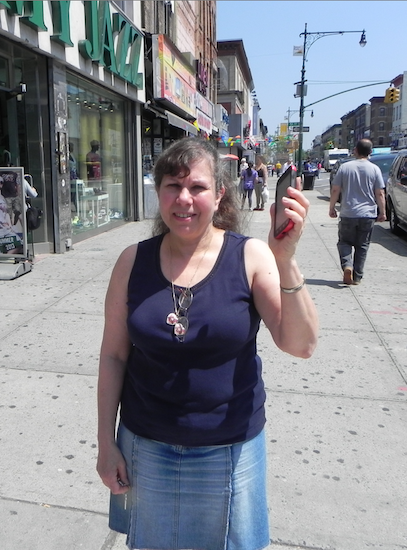 Sunset Park BID Executive Director Renee Giordano, standing on Fifth Avenue and 51st Street, says her Smartphone will be able pick up a WiFi signal on the street, thanks to the new technology upgrade. Eagle photo by Paula Katinas