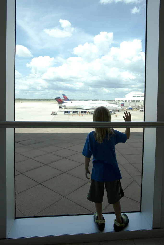  5-year-old Apollo Przystawik stands near a window at Southwest Florida International Airport to wave to the incoming planes on June 30, 2016 