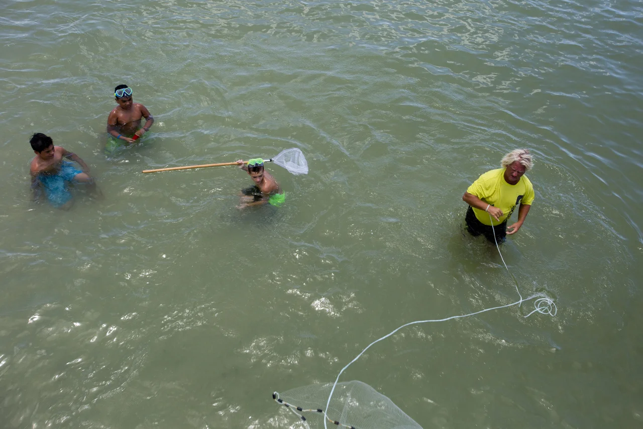  Aidan Escobar, left, Dylan Escobar, center, and Haze Hickman, right, watch as Tim Marshal cast nets near the Naples Pier on June 20, 2016. 