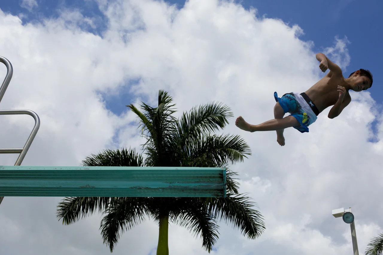  8-year-old Eduardo Ruiz takes a spin off the diving board at Sun-N-Fun Lagoon in Naples on July 8, 2016. 