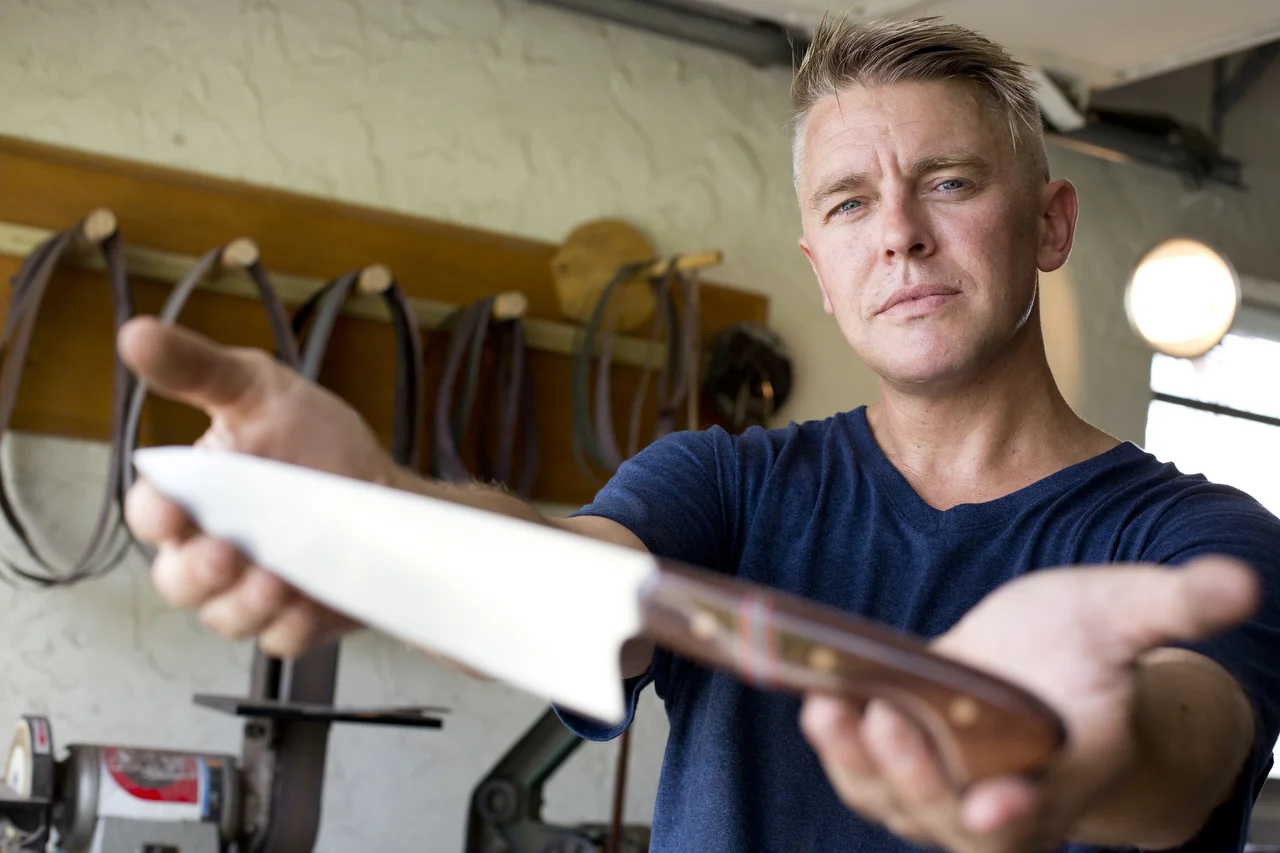  James Grosser, a bladesmith for his own cutlery business, poses with one of his handmade knives out of his shop in Naples on July 14, 2016. 