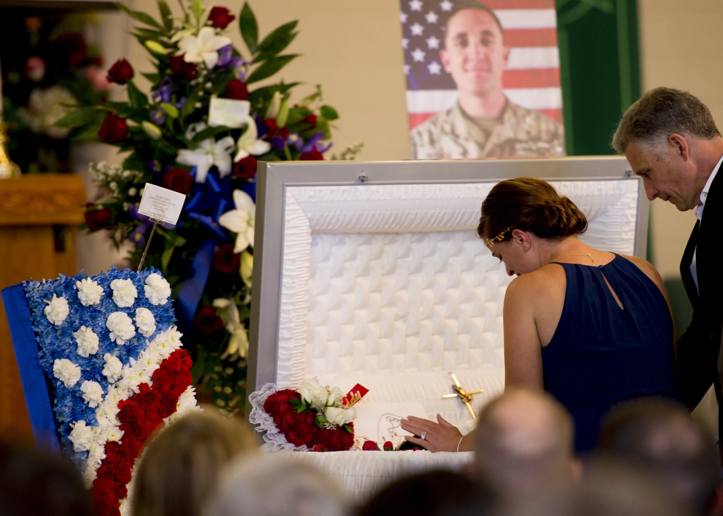  Samantha Houck reaches to touch her husband's head one last time before the closing of his casket at his funeral service on June 20, 2017. 