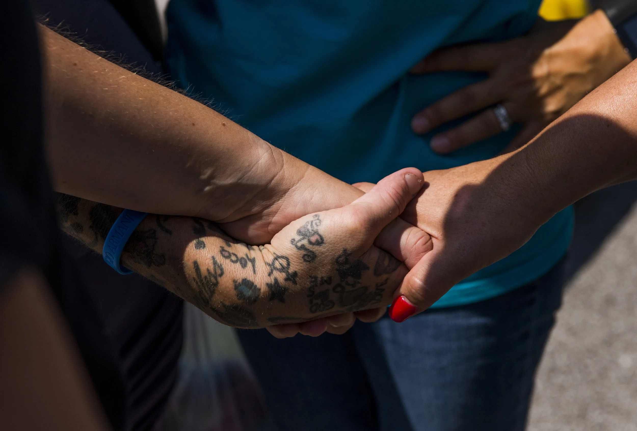 YAIPak volunteers hold a woman's hand as Founder Sherry Nicholson says a prayer for her during their homeless outreach on August 2, 2017. 