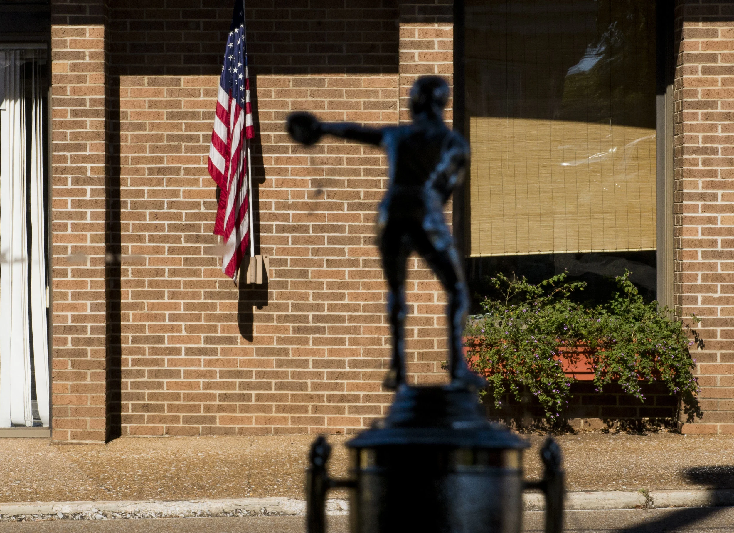  A boxing trophy from inside Paris Downtown Boxing Gym looks out to an American flag hanging across the street in Paris, Tennessee. 