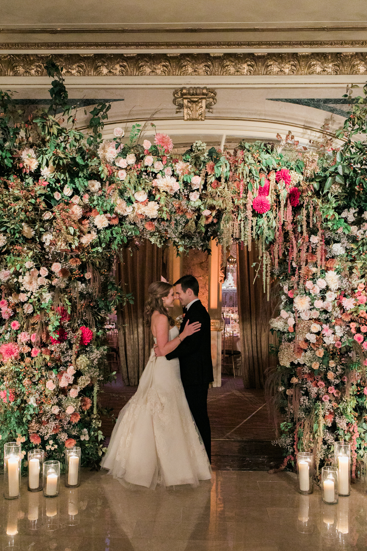 Bride and groom at Plaza wedding in front of flower arch