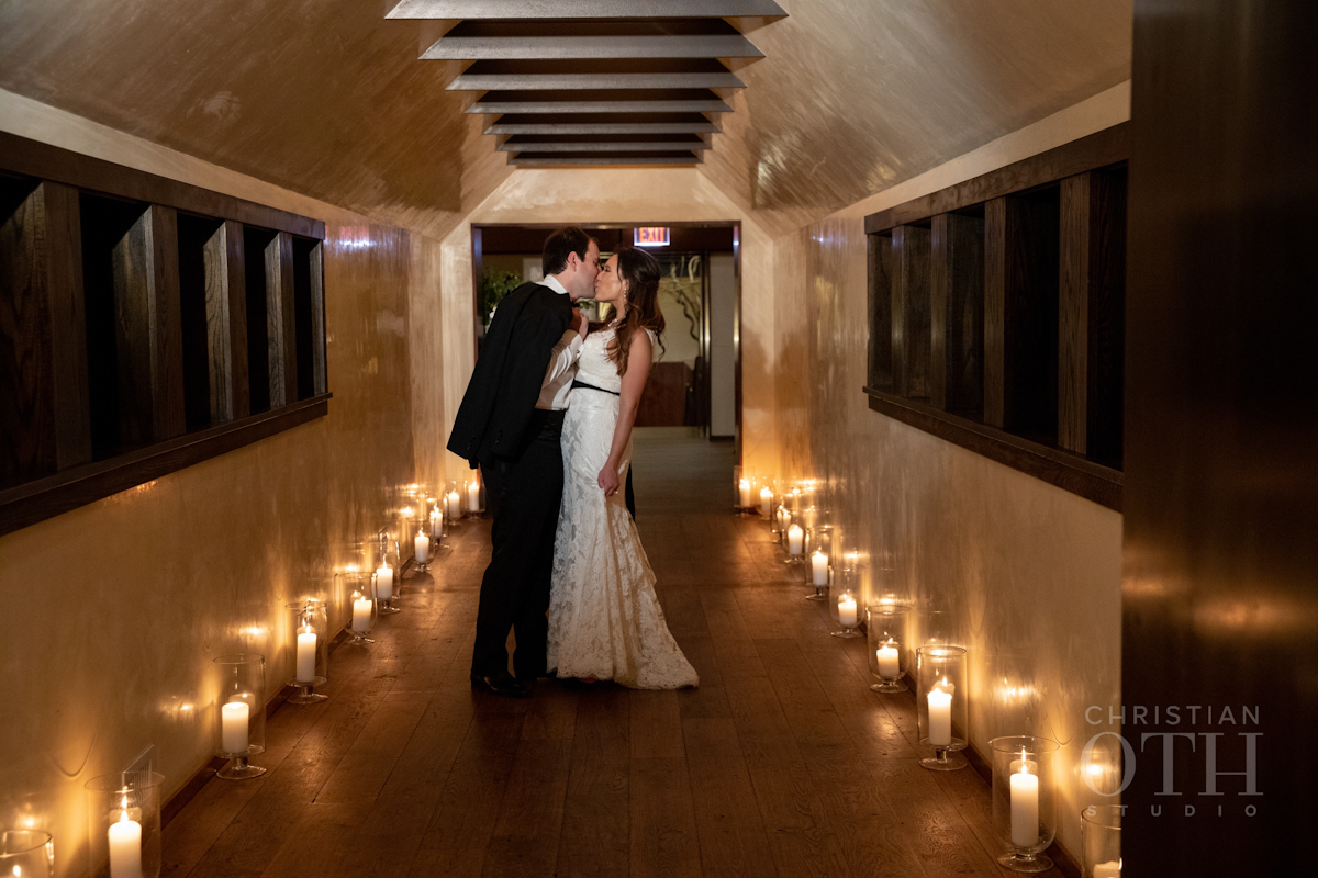 Bride and groom kissing in a hallway flooded with candlelight at Blue Hill at Stone Barns