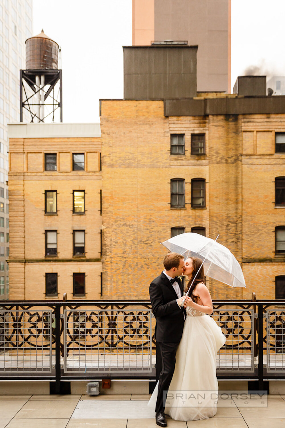 Rooftop bride and groom under umbrella