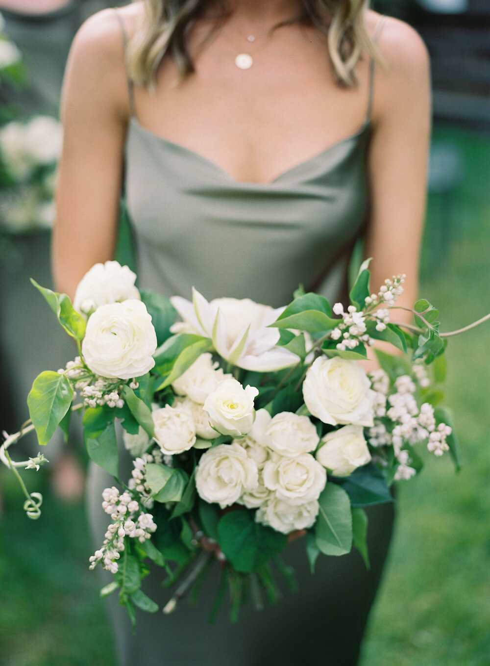 bridesmaid in green holding white bouquet