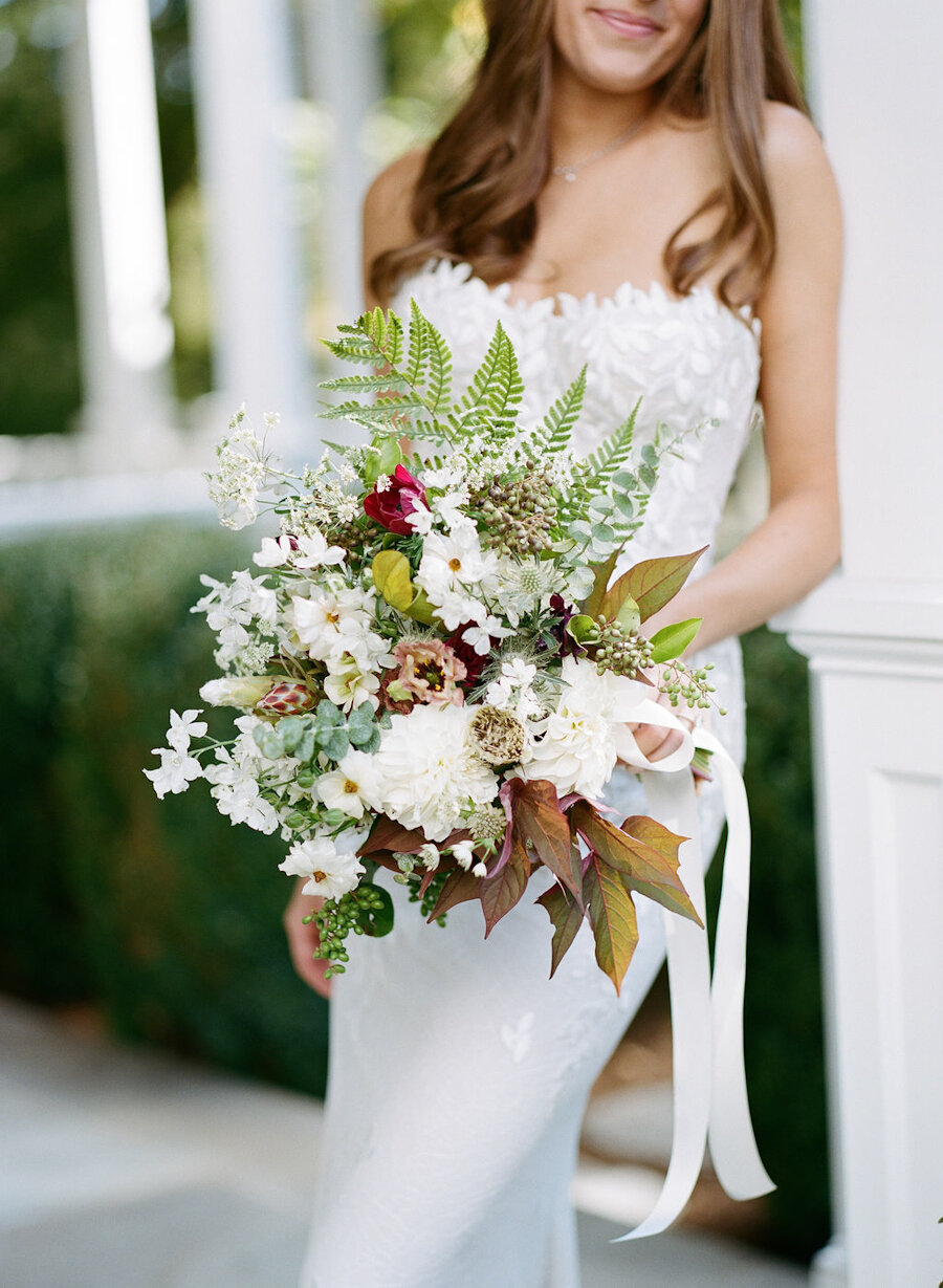 micro wedding bride holding white and green bouquet with fall foliage