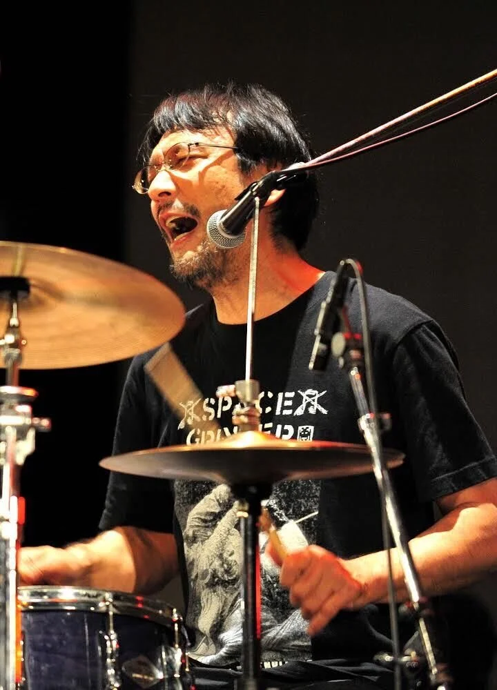 吉田達也 YOSHIDA Tatsuya (Drums, Voice)1961年、岩手生まれ。現代日本の前衛音楽シーンの最重要ドラマー／作曲家／インプロヴァイザー。80年代初頭から都内のライブハウスを拠点に演奏活動を開始。変拍子を多用しパワフルでポリリズミックでスピード感溢れる演奏スタイルで、数多くのグループに参加して活躍。85年に結成したRUINSは、そのソリッドなリズム・セクションによるエネルギーの爆発にオリジナル言語のヴォ−カルを乗せた革新的なサウンドで、海外でも高く評価され、頻繁に海外…