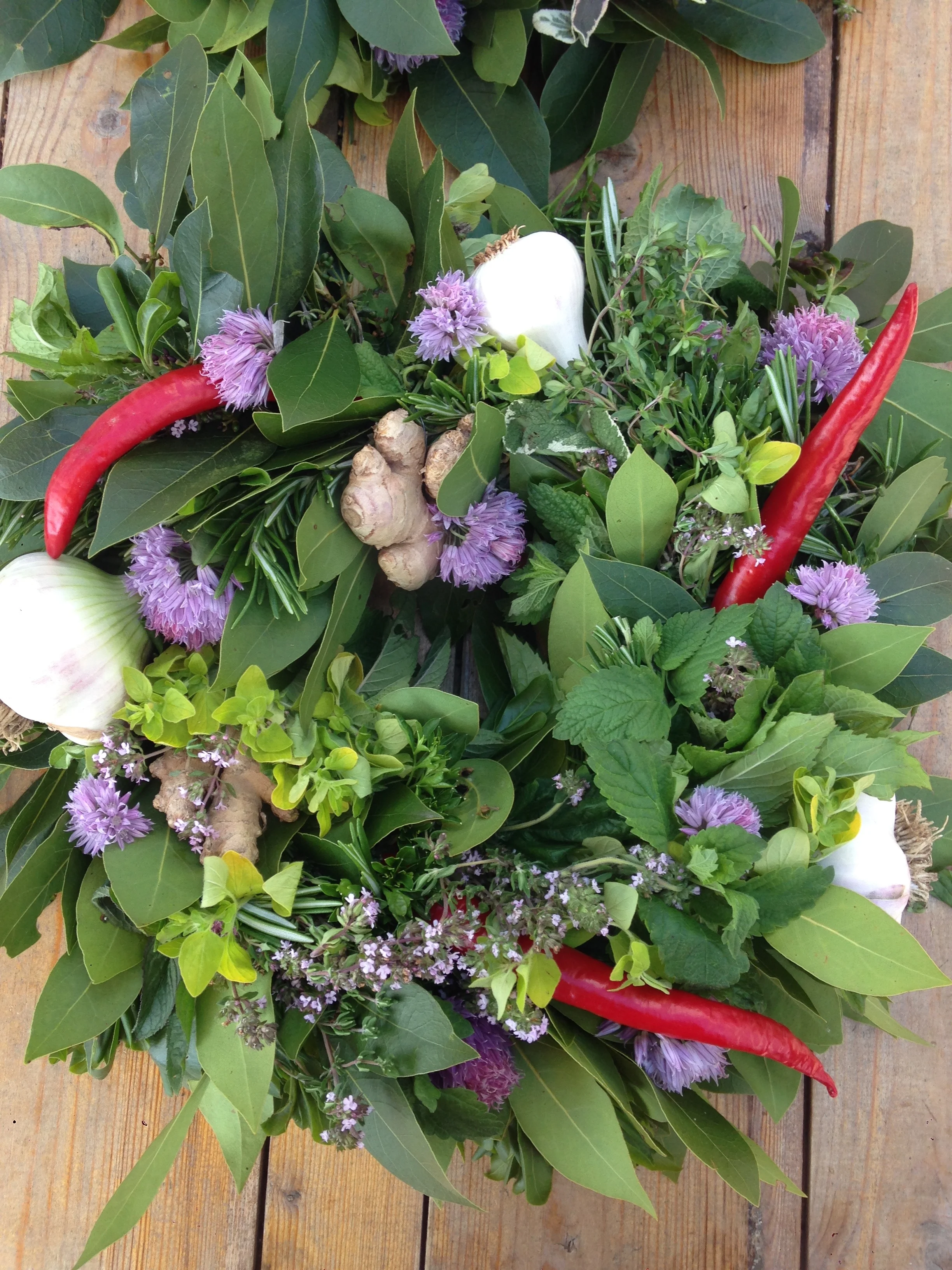 Fresh herb wreath with chili, bay leaf, rosemary, mint, ginger, garlic, thyme, chives, marjoram and sage.