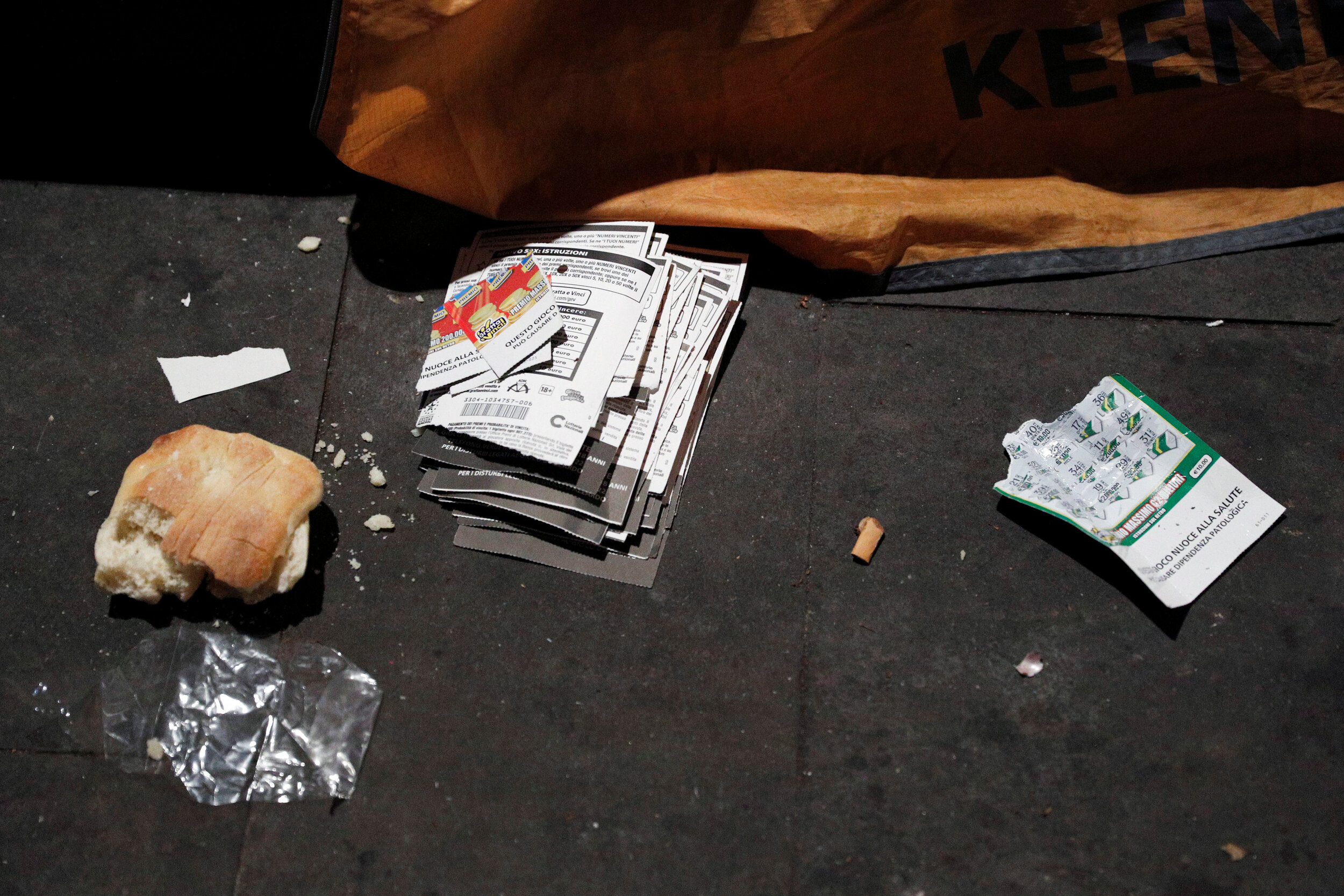  A piece of bread and a stack of lottery tickets are seen outside a tent where a homeless person lives in Rome, Italy, March 17, 2020. Since the coronavirus crisis, Red Cross workers have been increasing their daily activities to meet the growing nee