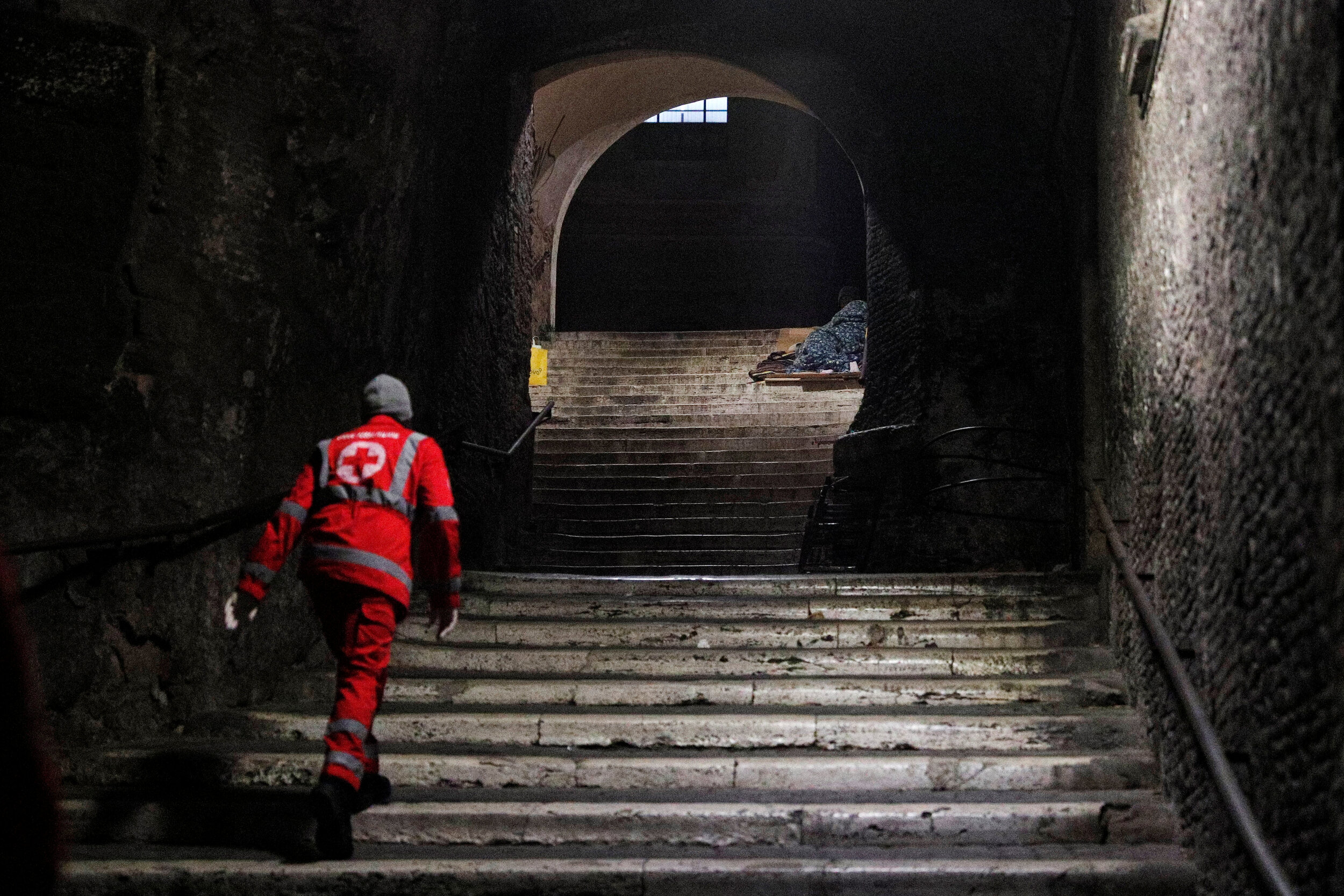  A Red Cross worker checks on a homeless person lying on a step near the Colosseum in Rome, Italy, March 17, 2020. Since the coronavirus crisis, Red Cross workers have been increasing their daily activities to meet the growing needs of the homeless i