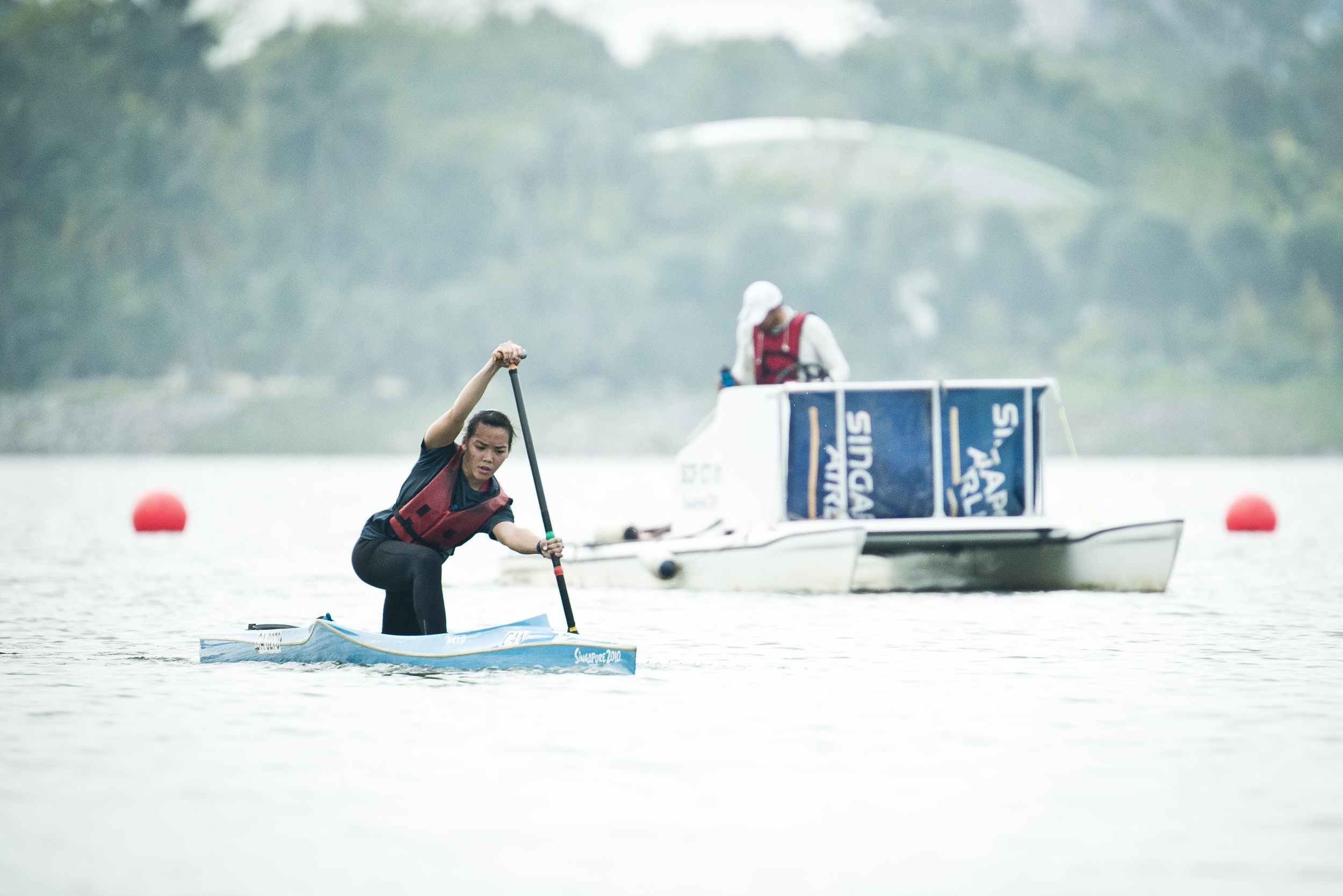 A canoeist paddles past a speed boat during training at the Marina Channel.