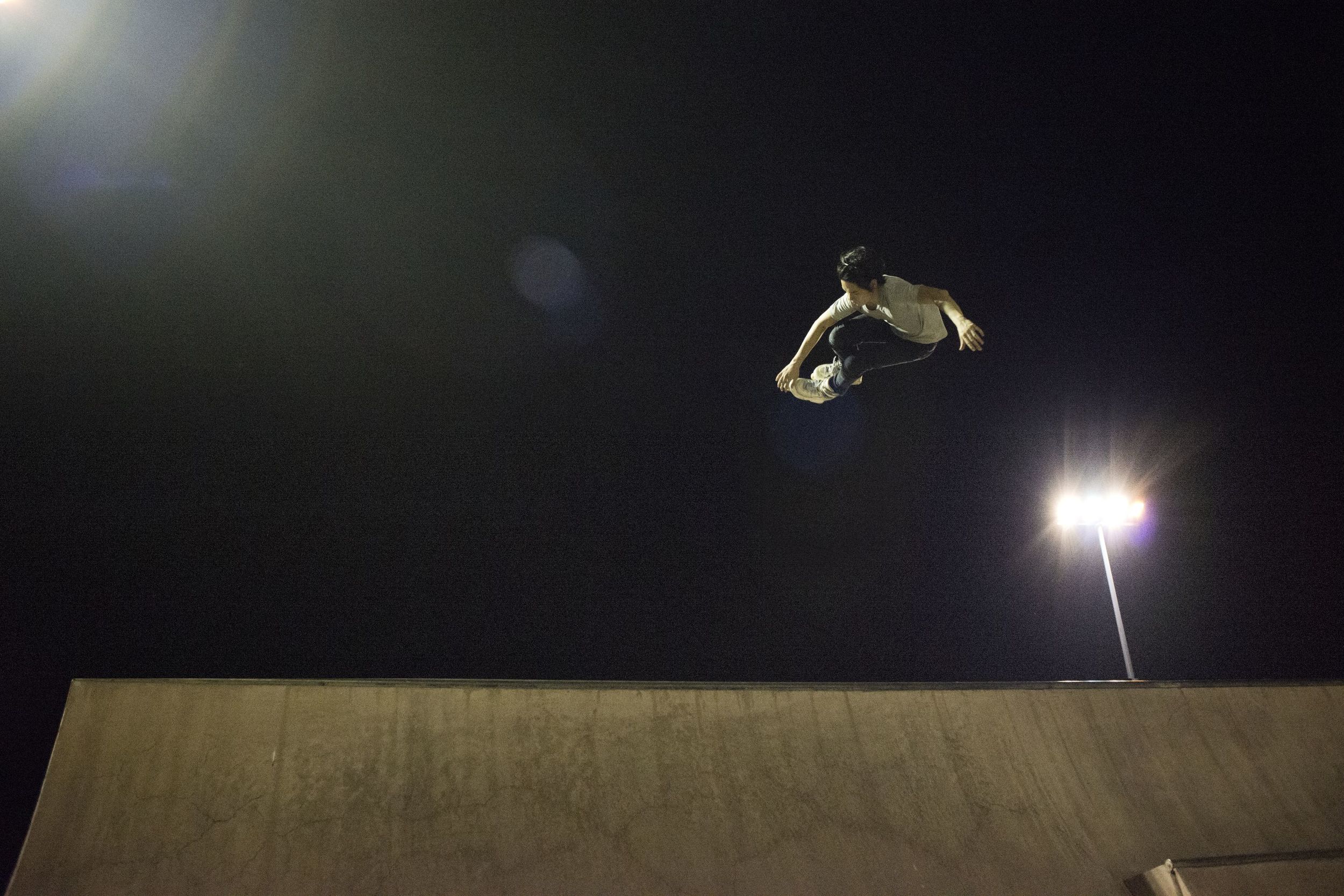 An inline skater executes a grab over the edge of the quarterpipe at the East Coast Skate Park.