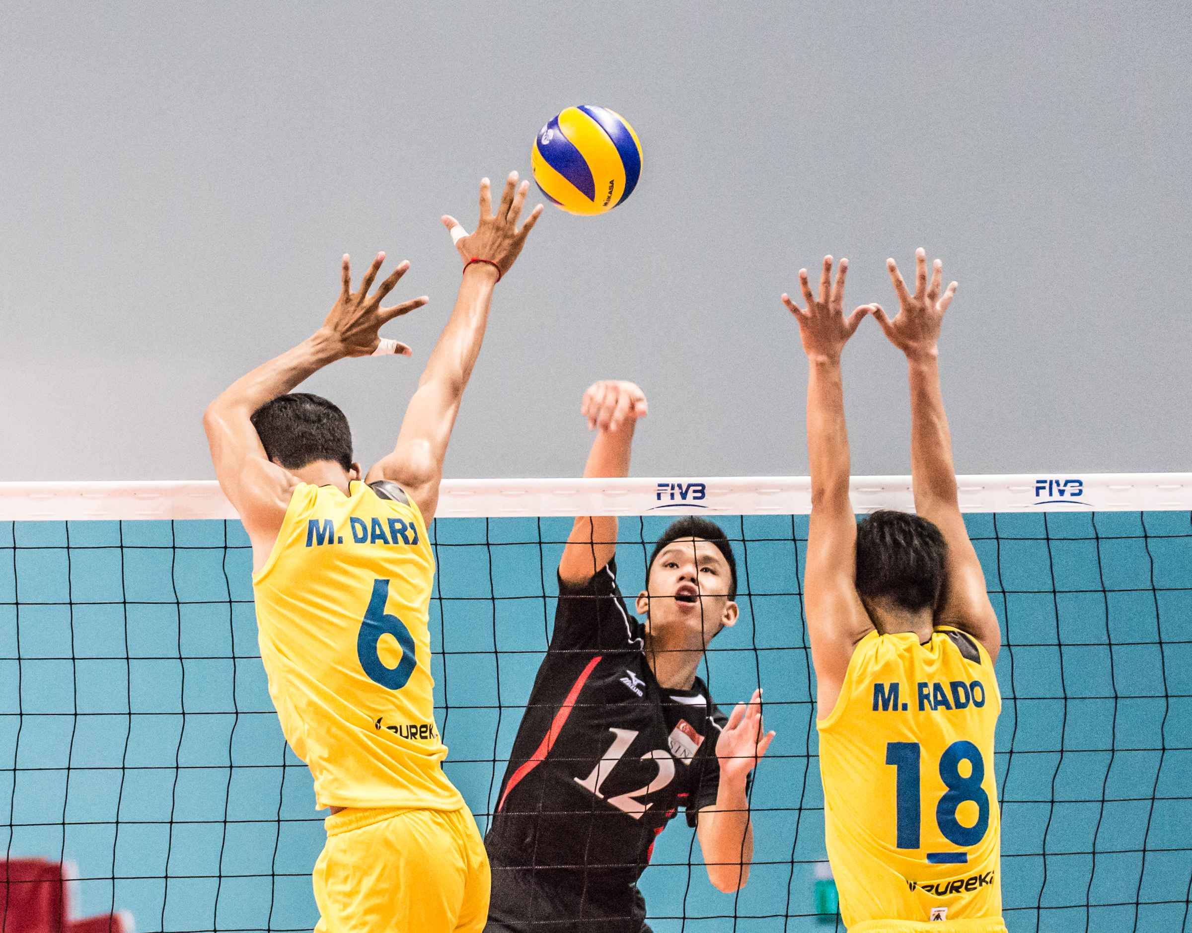 A Team Singapore player spikes the ball past two Cambodian players during a match at the OCBC Arena.