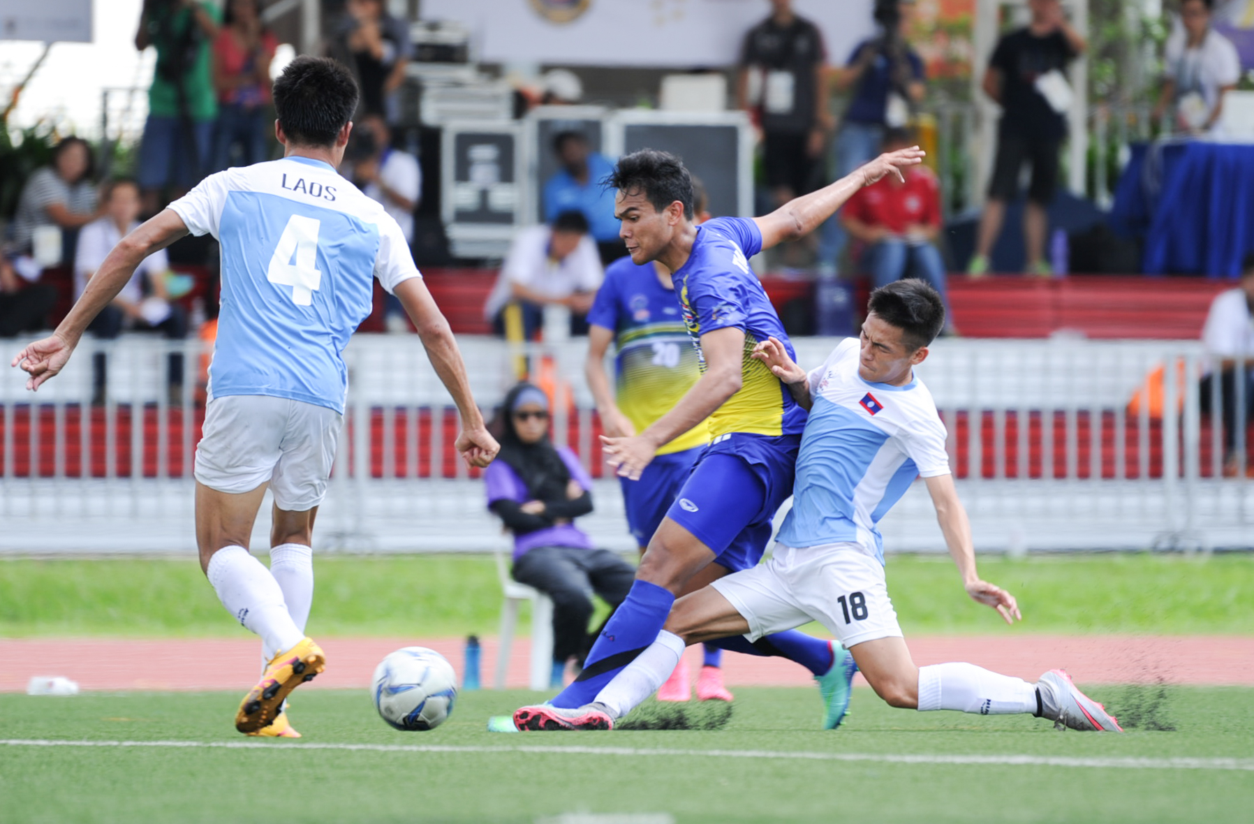 A Laotian player tackles a Thai player during the soccer competition of the ASEAN University Games at the Nanyang Technological University.