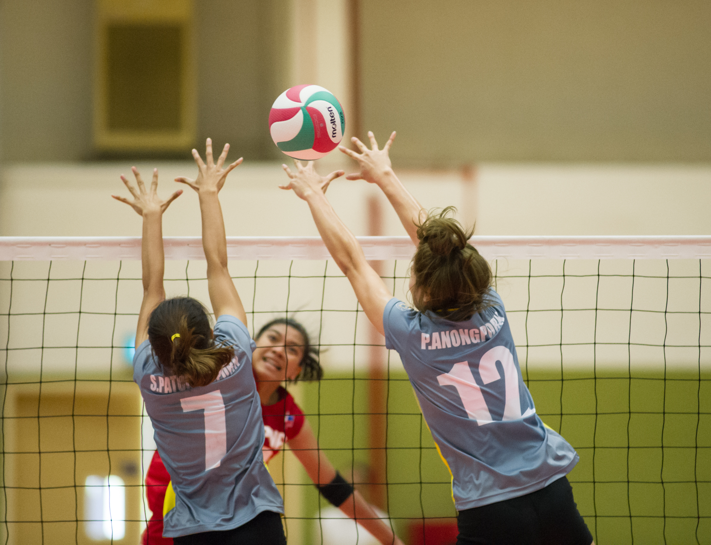 A Filipino player spikes past two Thai players during the volleyball competition of the ASEAN University Games at the National University of Singapore