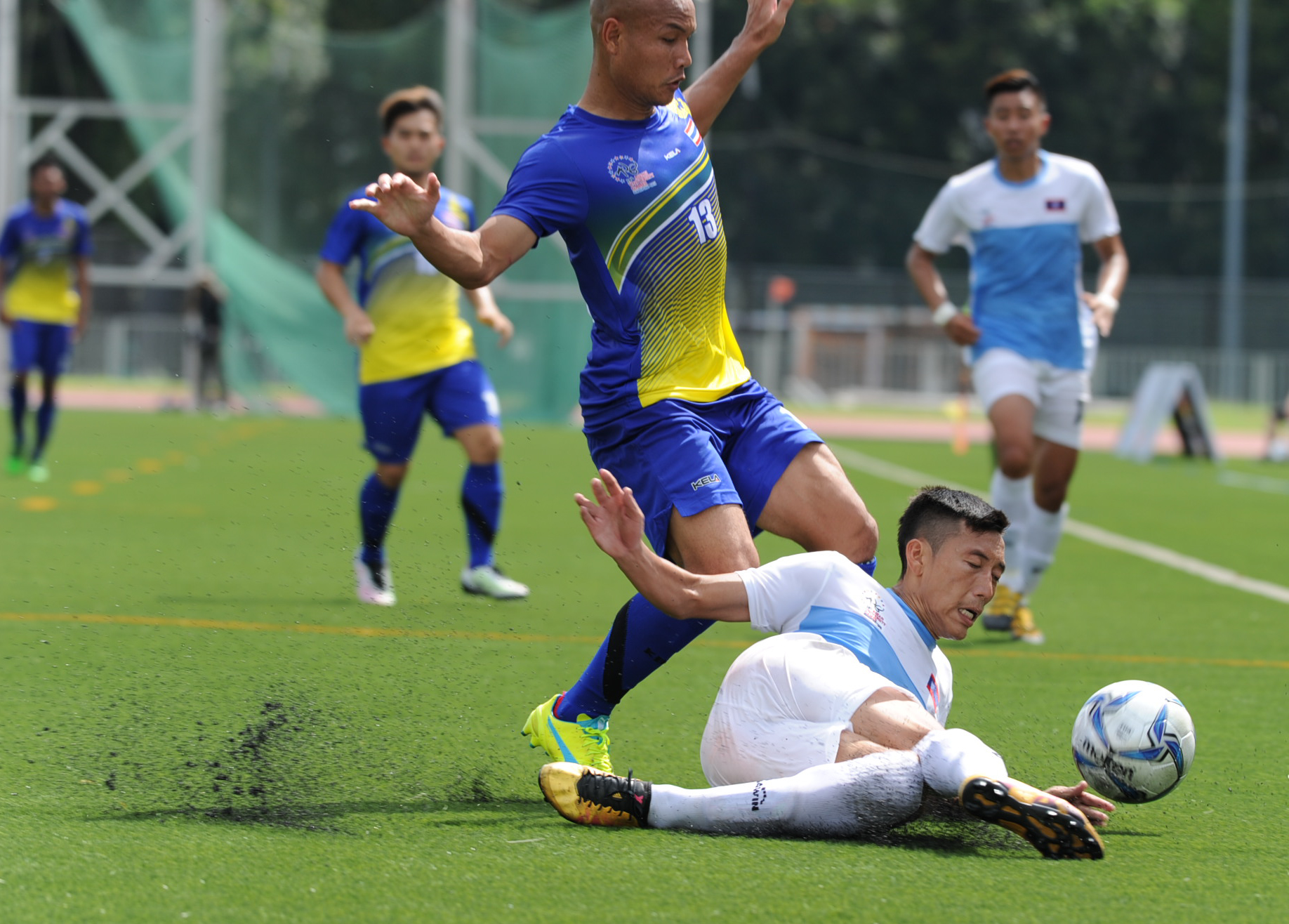 A Laotian player tackles a Thai player during the soccer competition of the ASEAN University Games at the Nanyang Technological University.