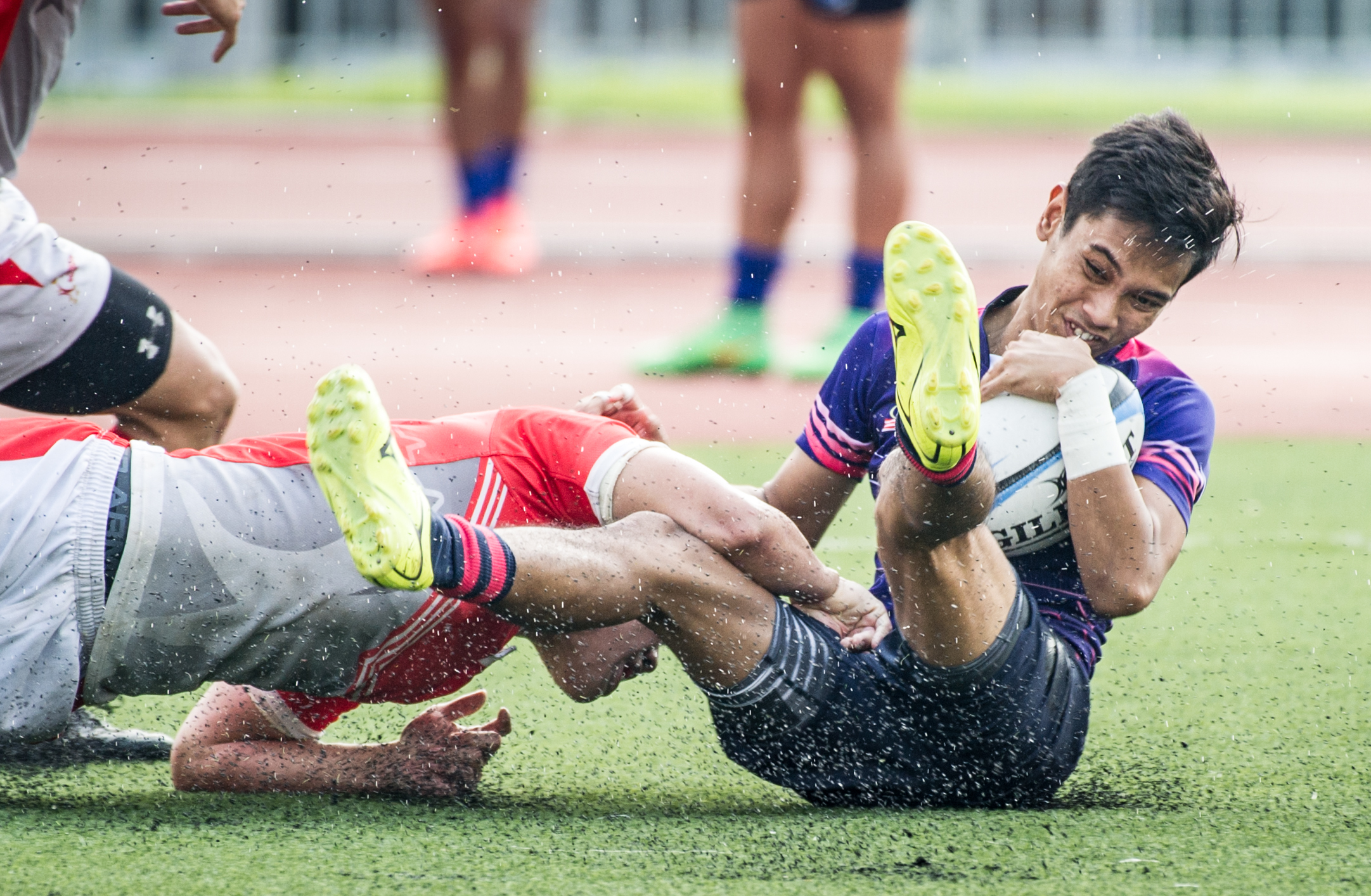 A Singaporean player tackles a Malaysian player during the rugby competition of the ASEAN University Games at the Nanyang Technological University.