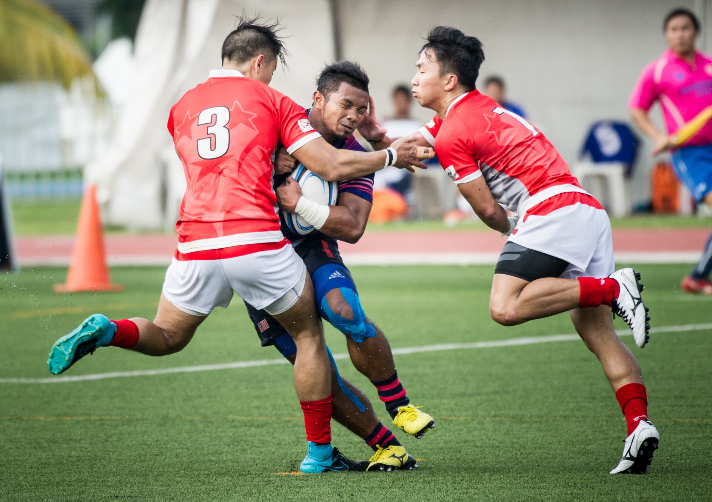 Two Singaporean players attempt to tackle a Malaysian player during the rugby competition of the ASEAN University Games at the Nanyang Technological University.
