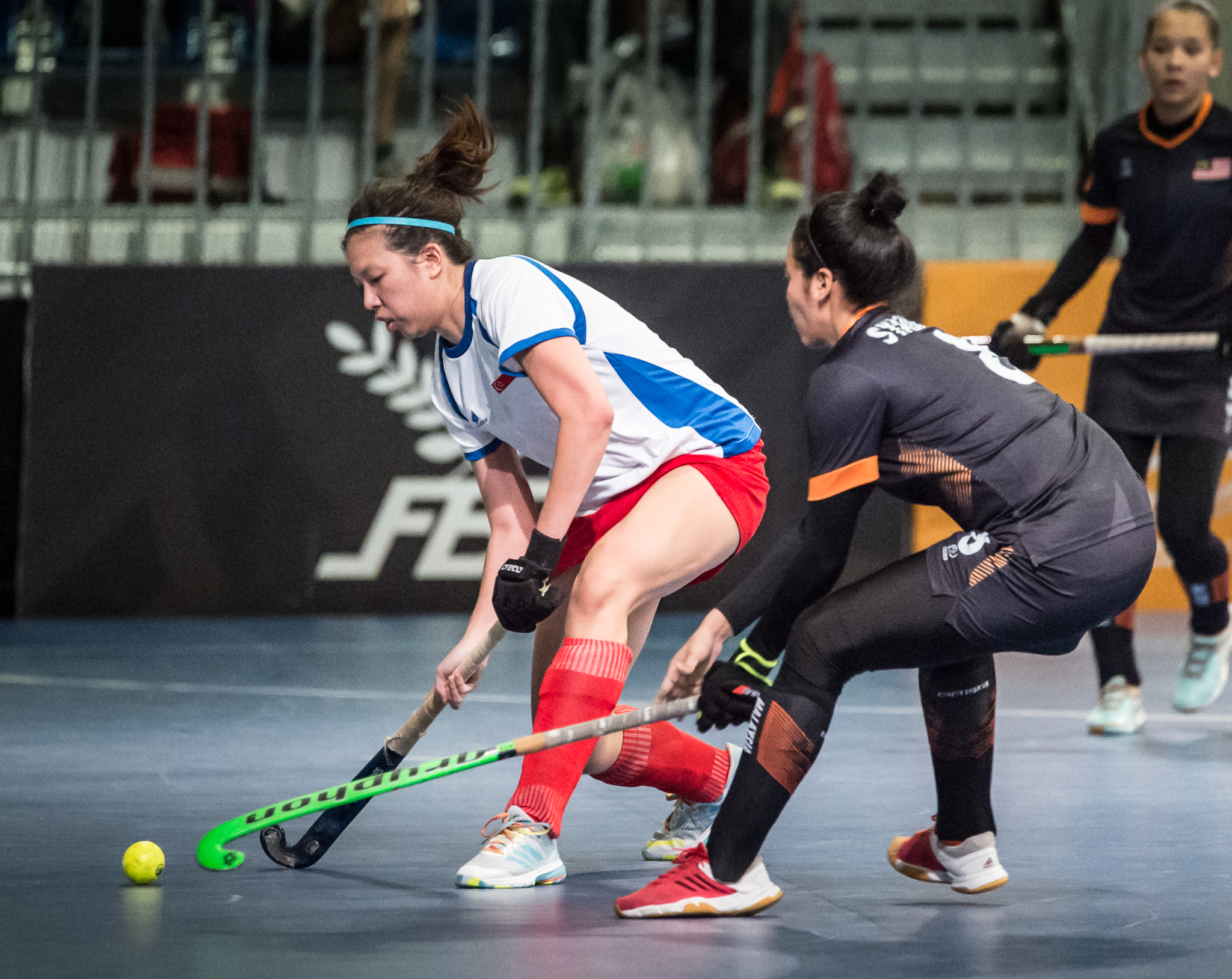 A Singaporean hockey player attempts to dribble past a Malaysian opponent during the SEA Games at the Malaysian International Trade and Exhibition Centre.