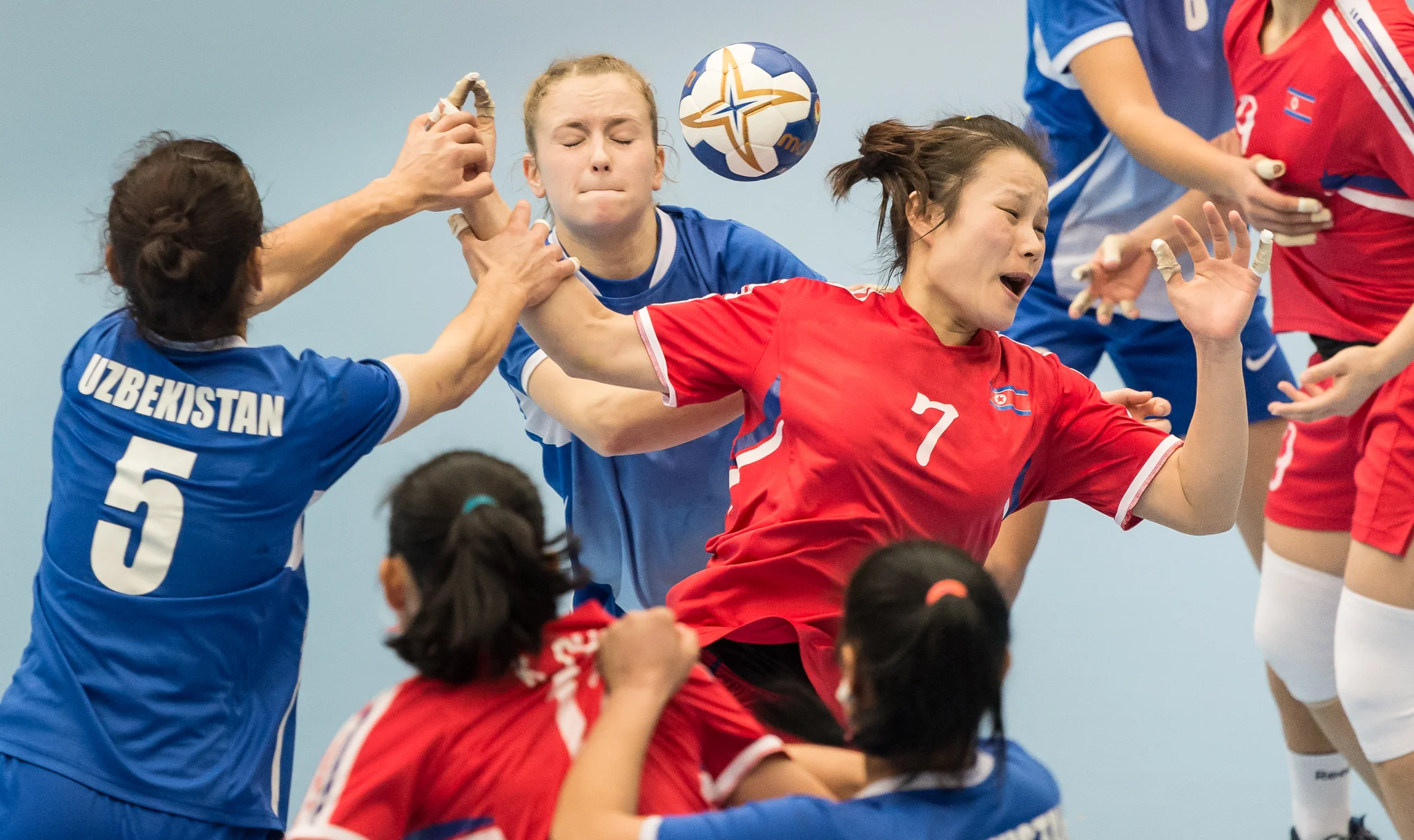 Uzbek players grab a North Korean player's arm during an International hand ball match at Our Tampines Hub.