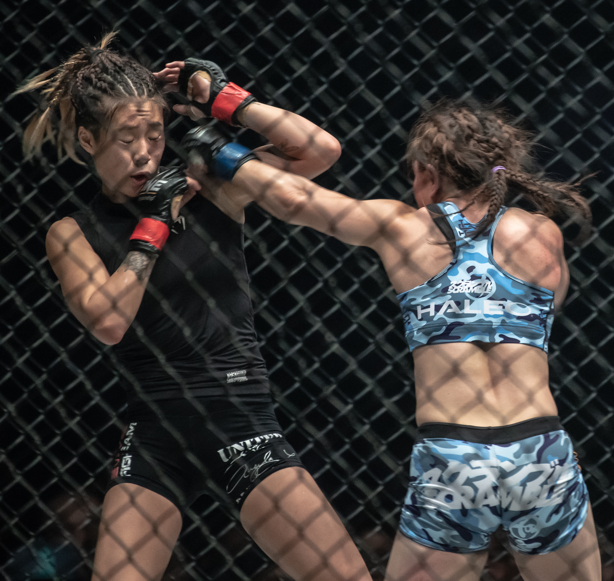 A Japanese MMA athlete punches her Singapore opponent during a One Championship World Title match at the Singapore Indoor Stadium.