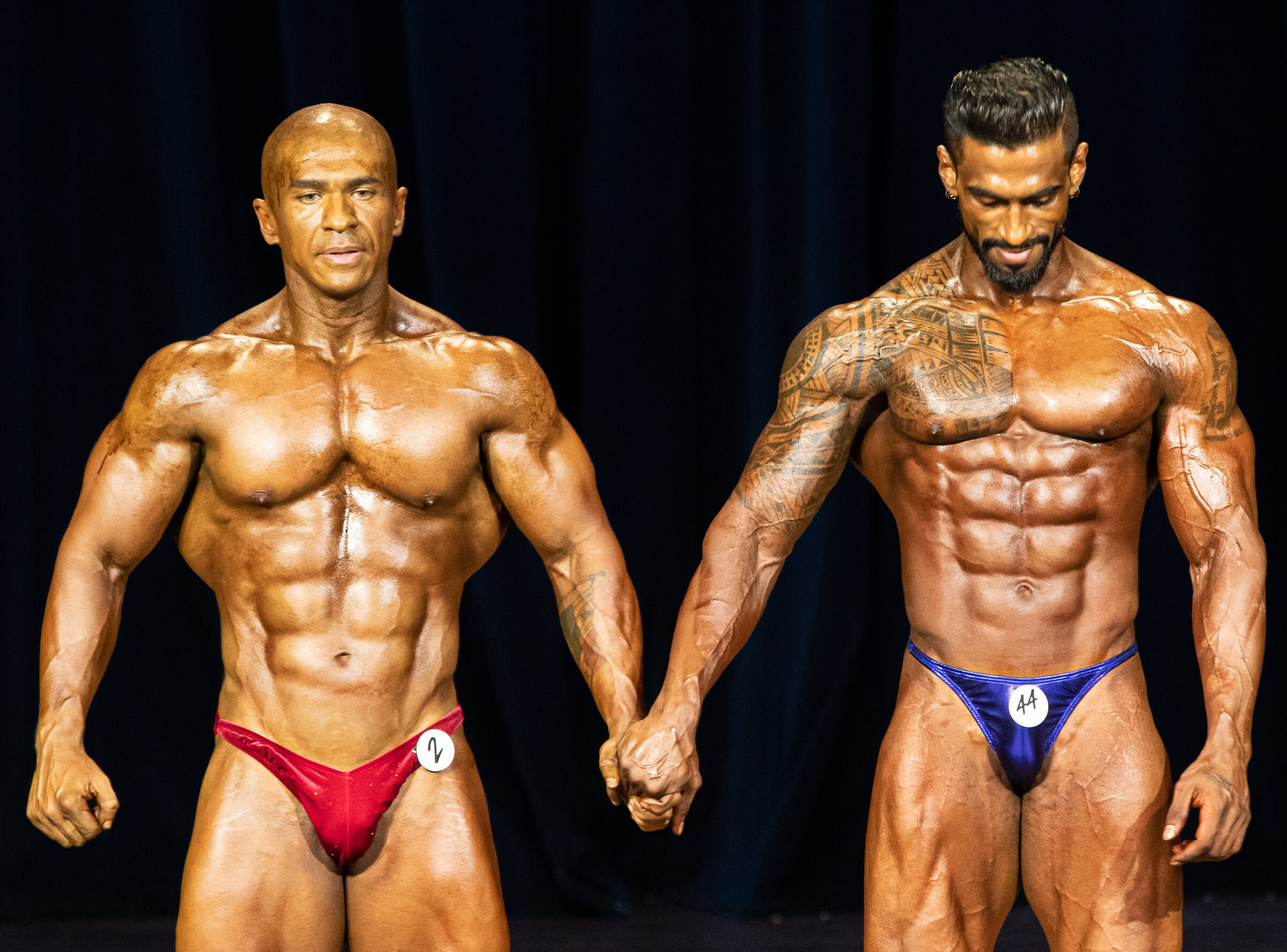 A Panamanian and Malaysian competitor holds hands during the IFBB Regional Bodybuilding Finals at the Kreta Ayer People's Theatre.