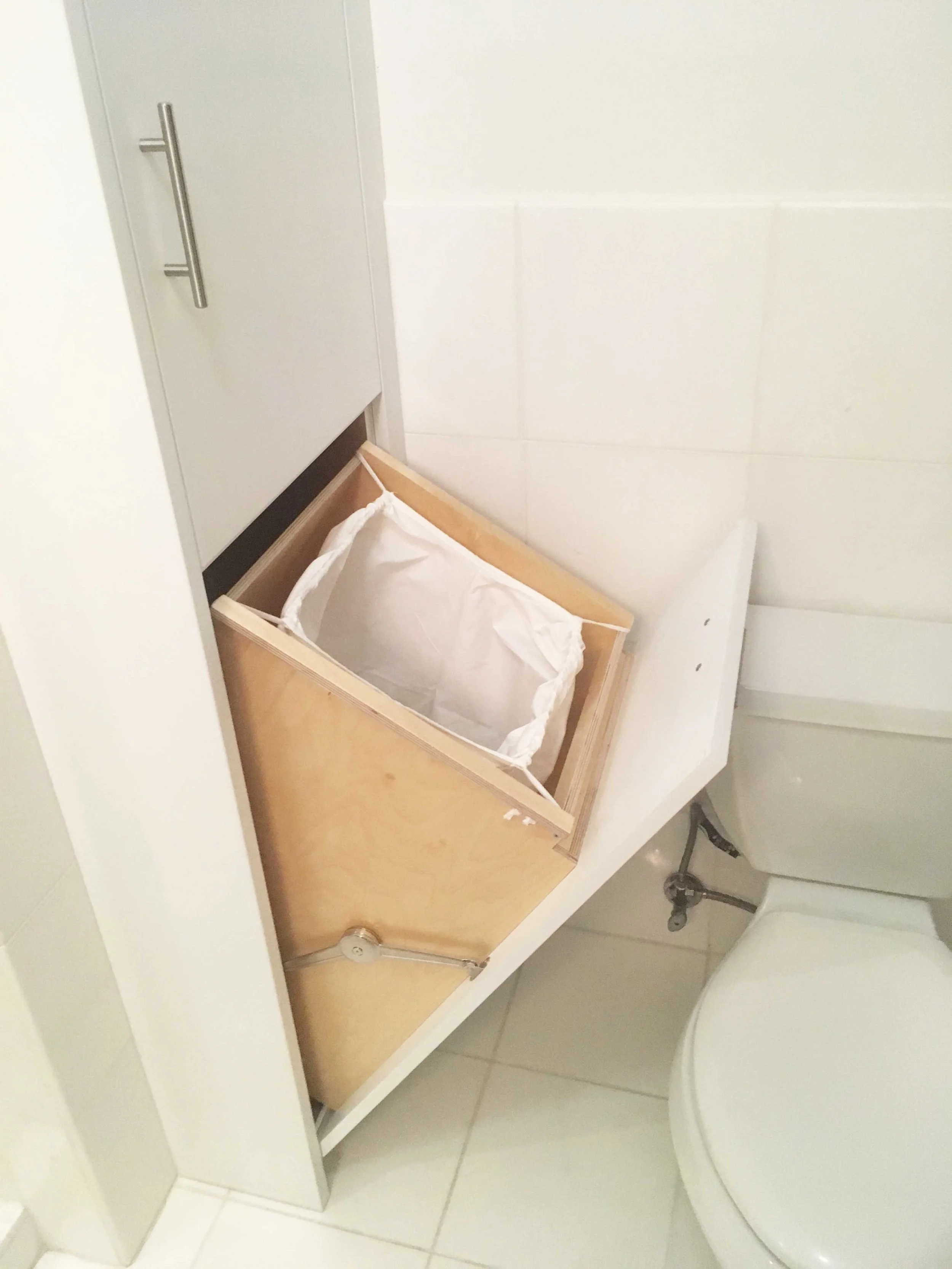 This cabinet hides the bathroom garbage can.