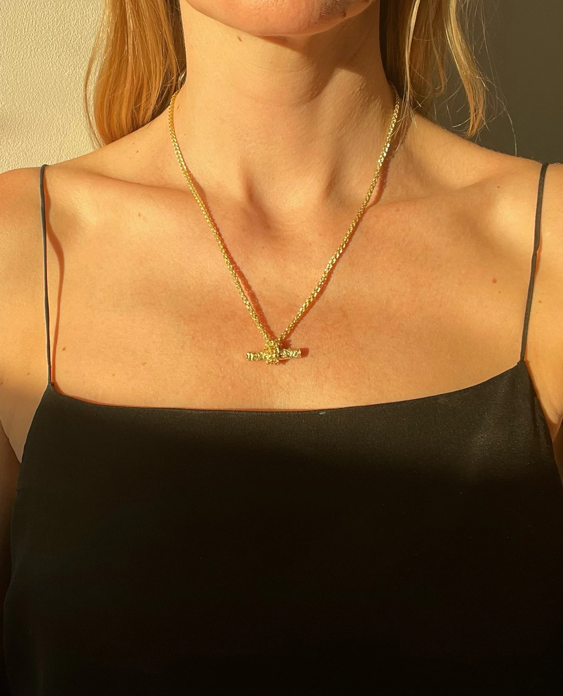 A model wearing a contemporary gold t bar necklace