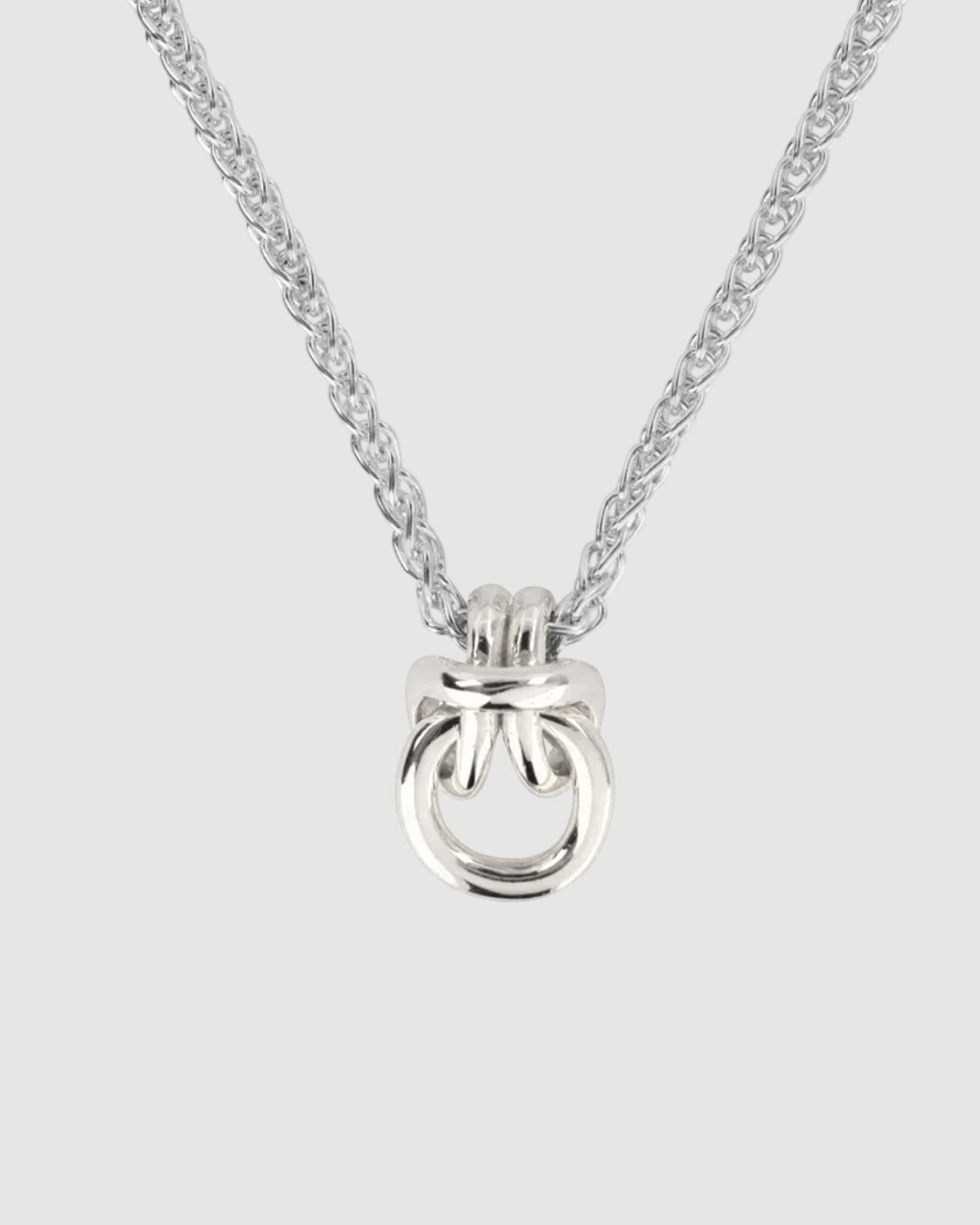 A heavy silver knot pendant necklace strung on a sturdy spiga chain