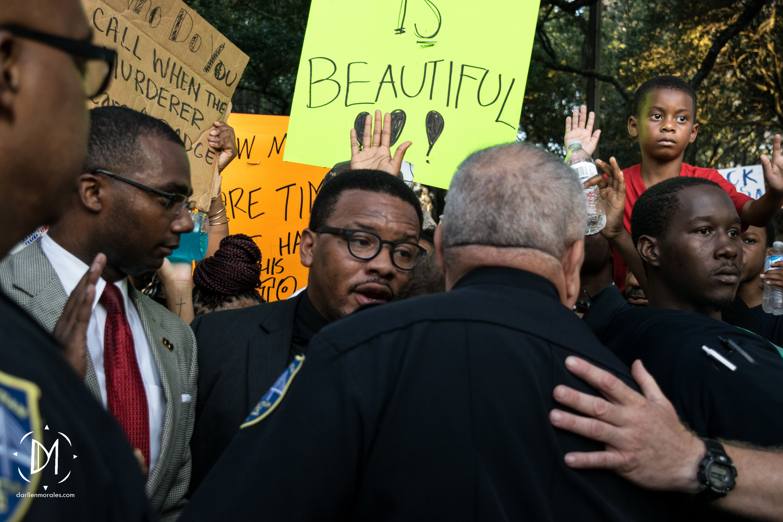   Activists shout, "Hands up, don't shoot" as local pastor, Jomo Johnson and the police discuss the march's route.    -July 12, 2016  