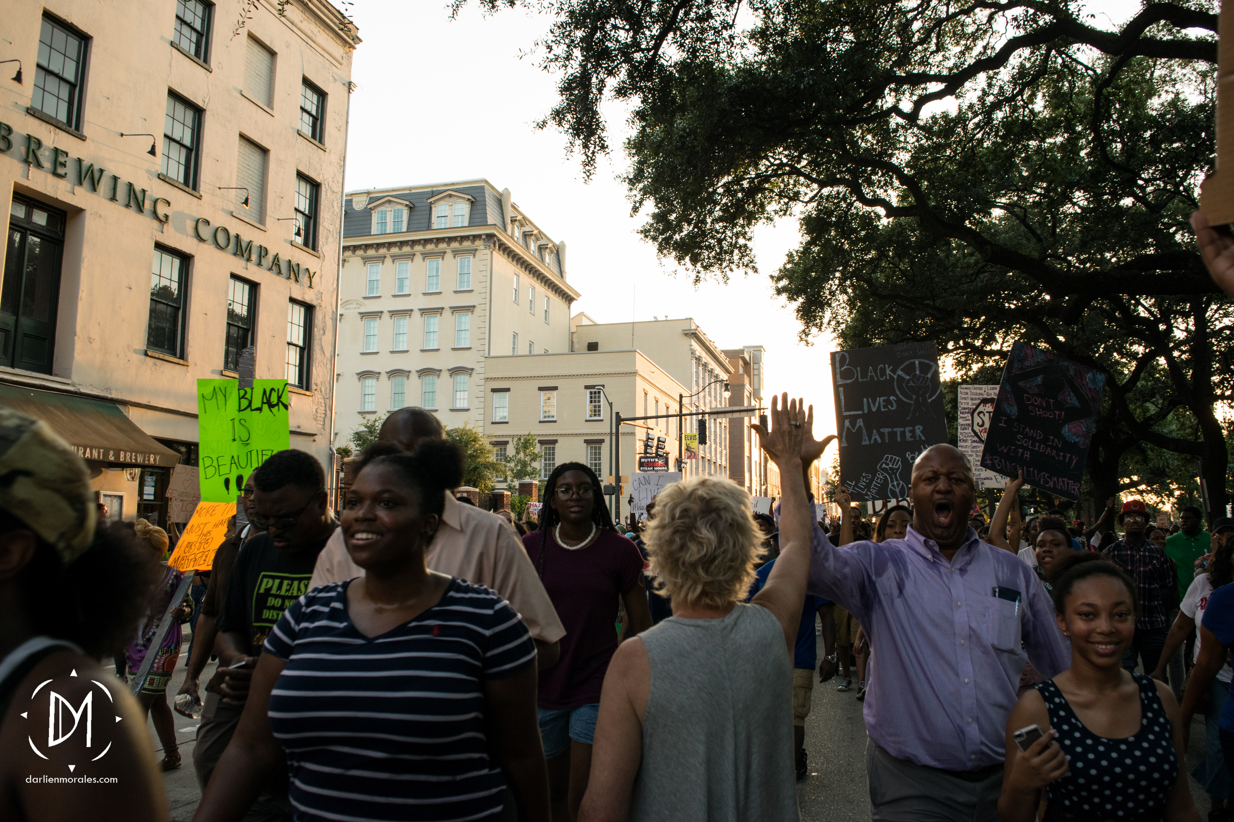   A women that is not part of the protest, stands in the middle of the crowd to high five people passing by.    -July 12, 2016  