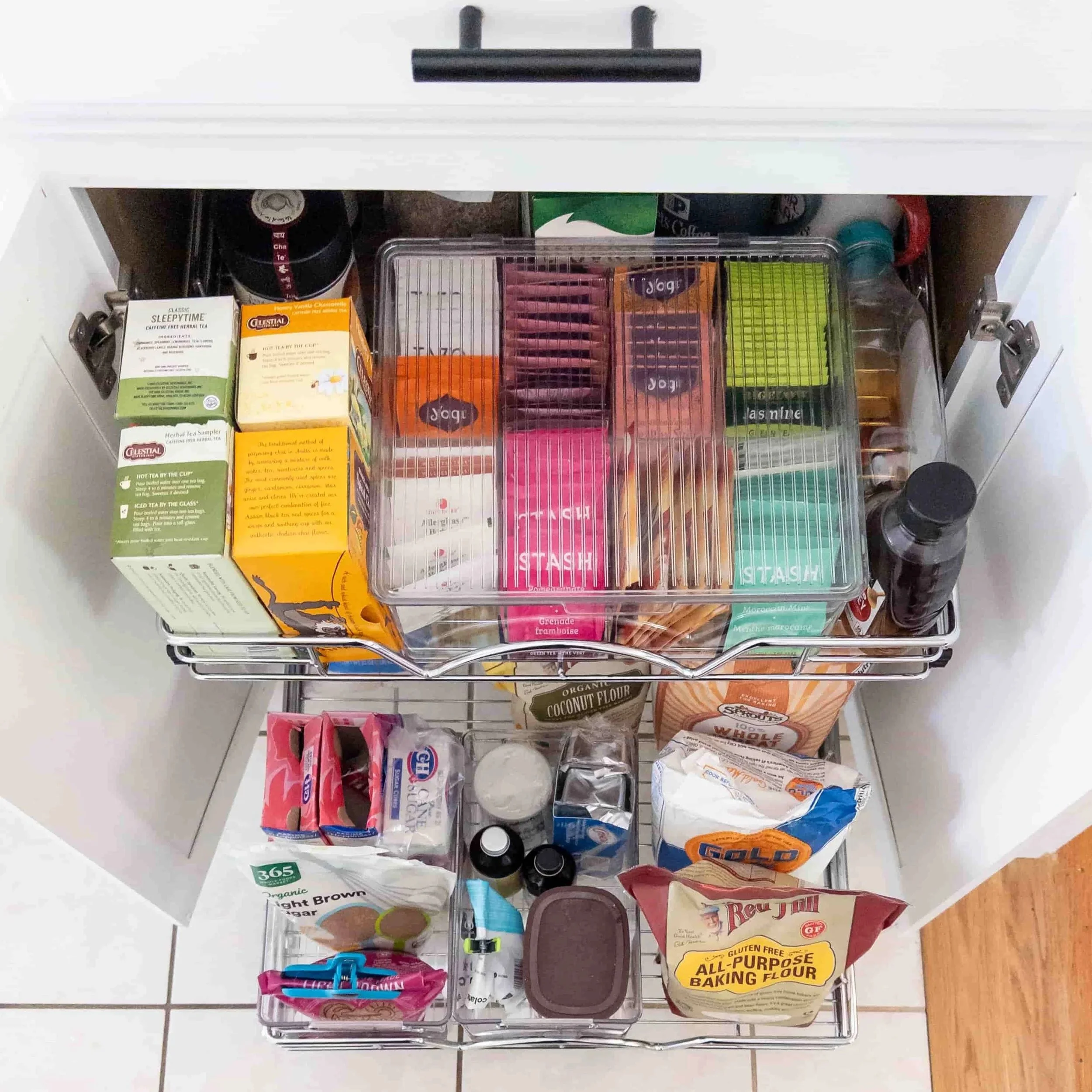 Open Kitchen Cabinet to show two newly installed pullout shelves organized with teas and baking supplies 