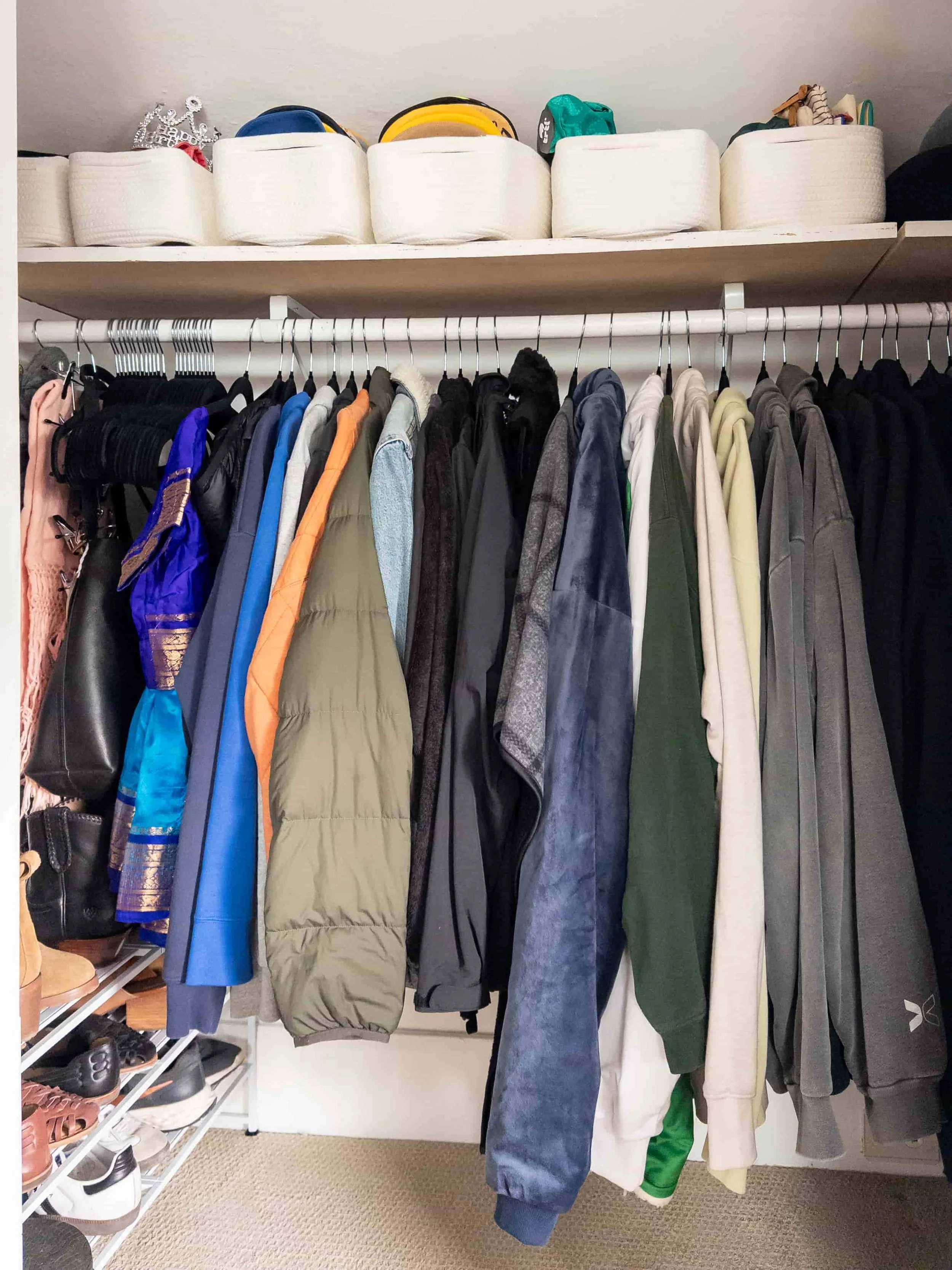 Organized Bedroom Closet with hanging clothes, shoe rack and baskets on top shelf