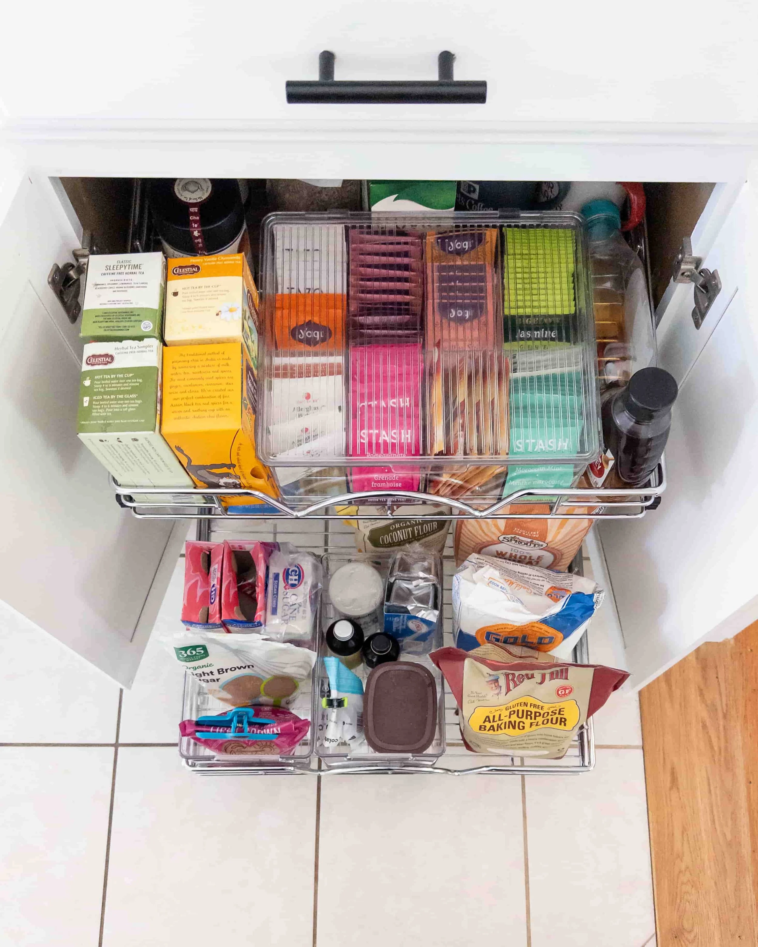 Open Kitchen Cabinet to show two newly installed pullout shelves organized with teas and baking supplies 