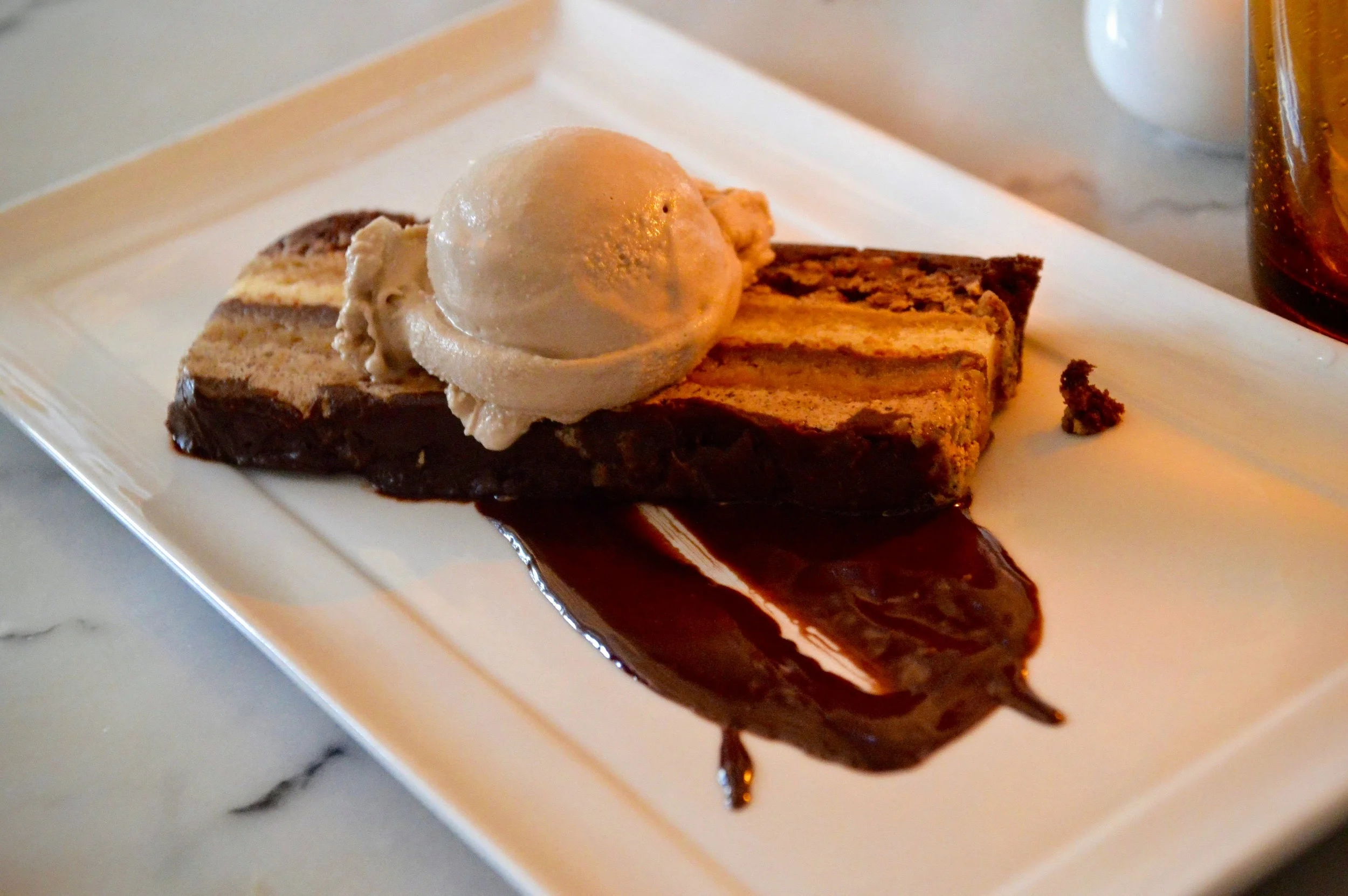 Dark Chocolate Opera - Layered sponge cake soaked in coffee syrup, bittersweet chocolate sauce, hazelnut crunch, bourbon gelato