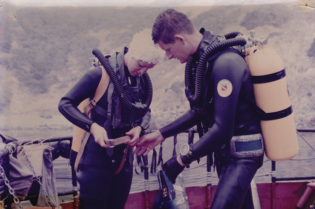 Tom, in early double hose regulator, helps a student with her gear for a dive at the Channel Islands.