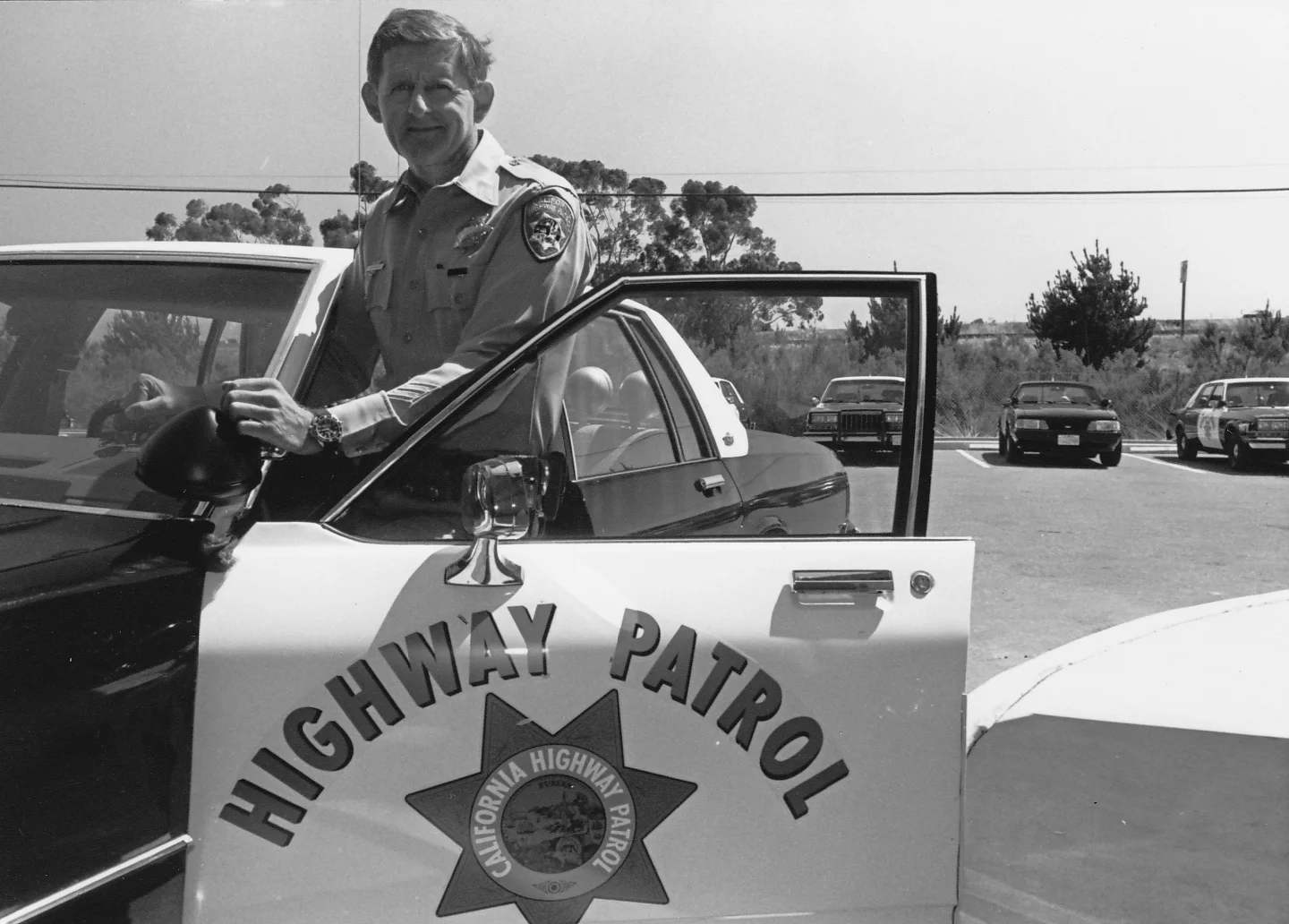 Officer Tom Campbell poses by his California Highway Patrol car during the 1980's
