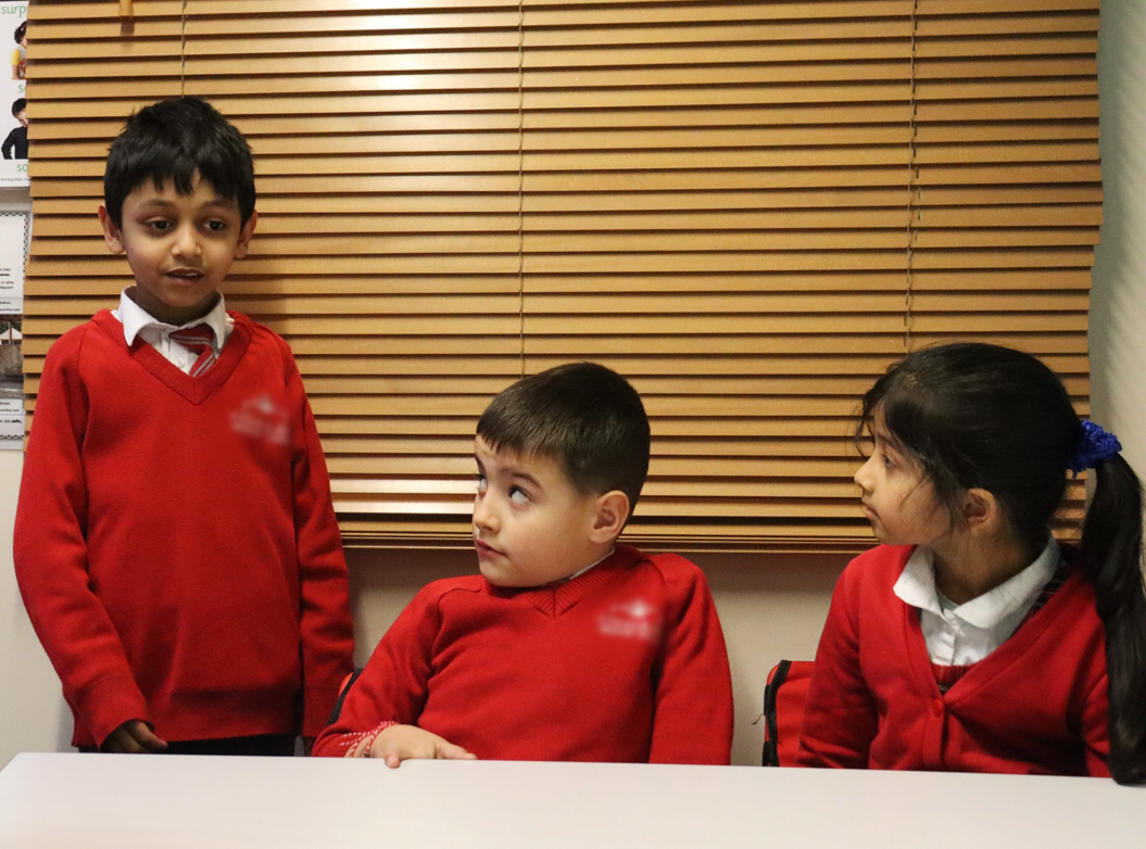 A pupil standing to speak while two peers listen closely