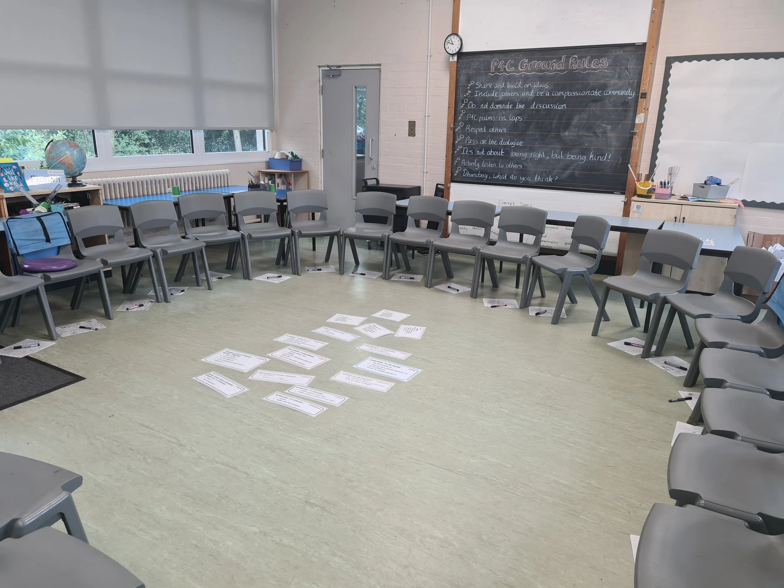 Chairs arranged in a circle, P4C ground rules on the board, talk prompts on the floor