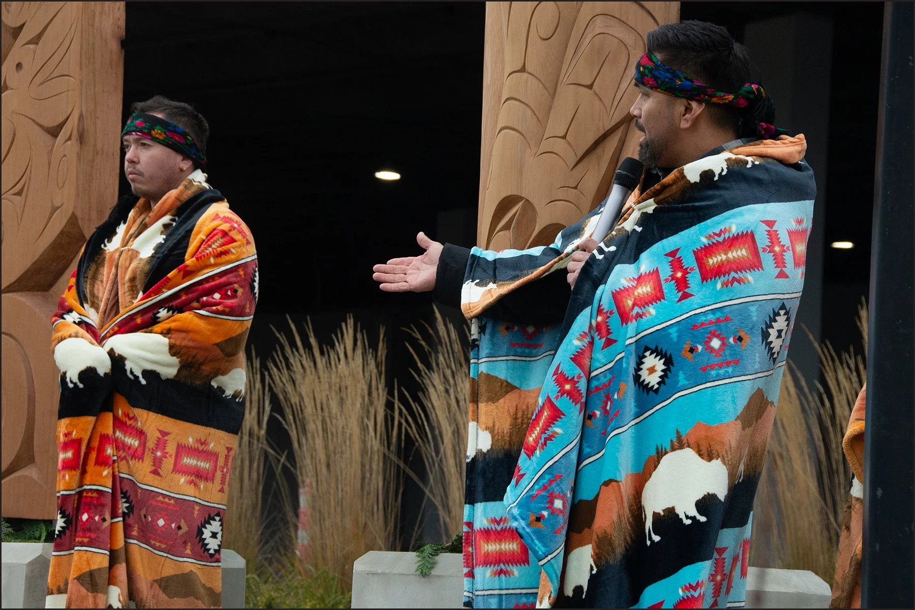  Bear describes the significance of his work at the blessing of pole representing four of five W̱SÁNEĆ Nations (November 2025). This collaborative project between W̱SÁNEĆ Nations, the City of Sidney, the VAA, and Amazon acknowledges the Peoples who h