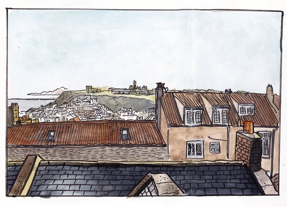 Vista de techos de casas y colina con fortaleza en el fondo.