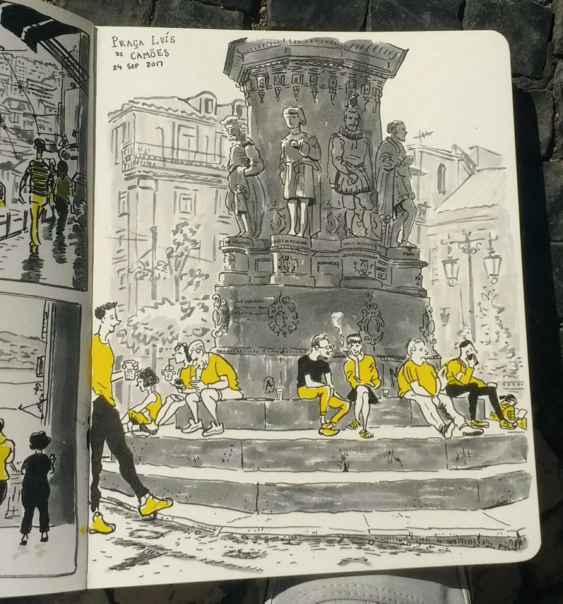 Dibujo de la fuente en la Plaza Luis de Camões, en Lisboa, con varias personas sentadas en sus escalinatas y otras caminando, algunas con camisetas y zapatos amarillos. La escena es al aire libre y en el fondo hay edificios históricos y farolas. Fech