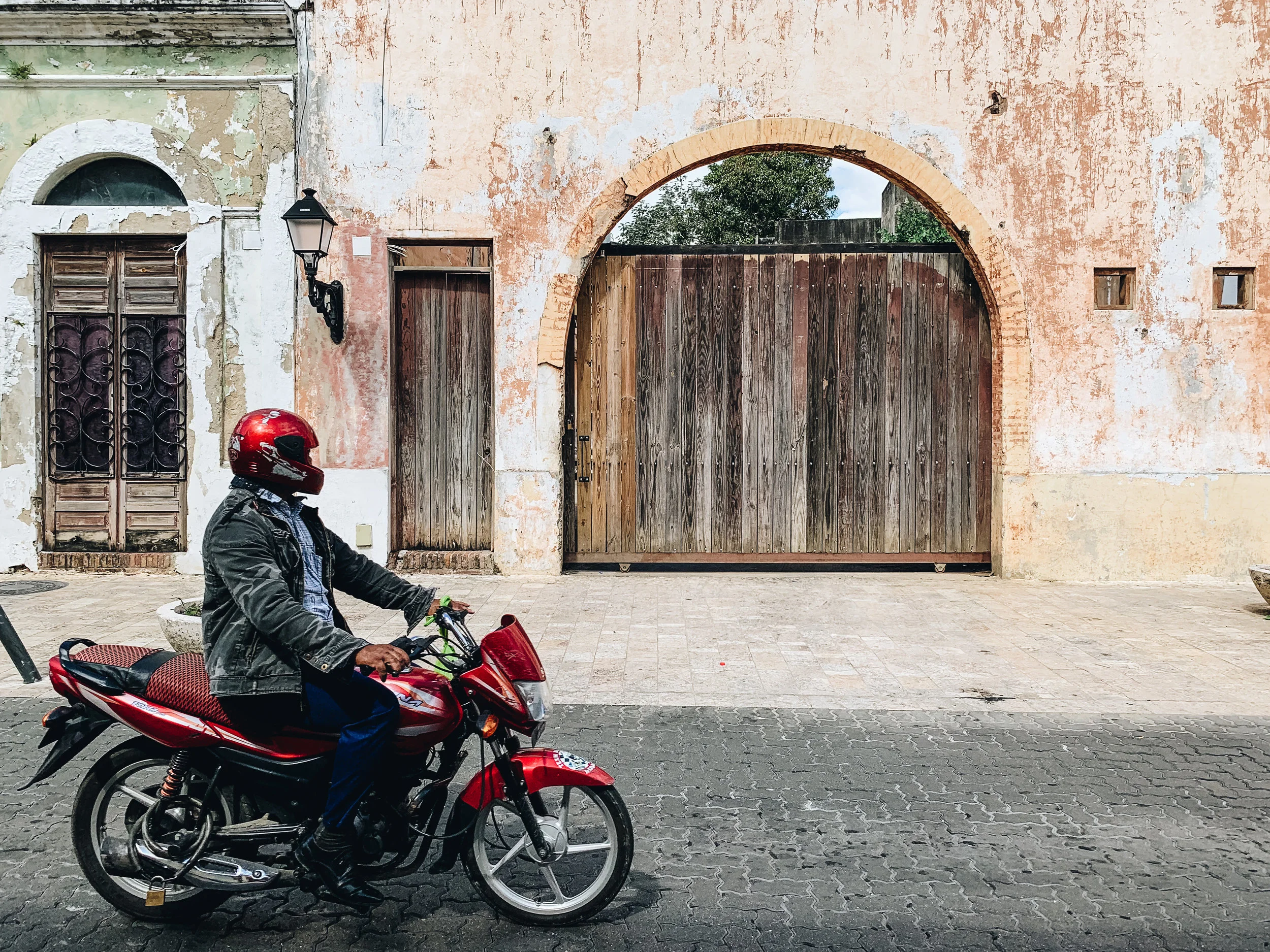 Biker's red toy stands out against peeling textures of old wall in Zona Colonial, Dominican Republic