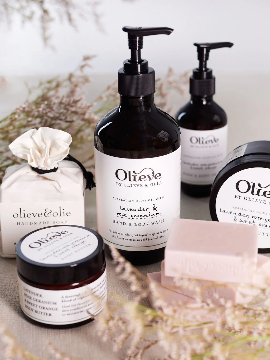 Olieve and Olie skincare products with some florals on a bench
