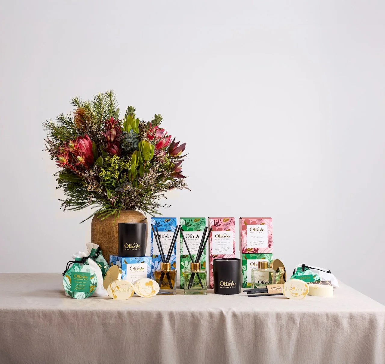 Diffusers, candles and soap with gold mica on a table with a bouquet of flowers in a vase